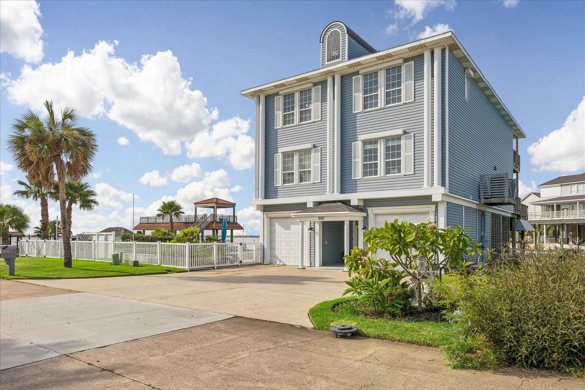 426 Sunset Circle, Tiki Island, TX 77554 Large windows complete with storm shutters throughout the home, spacious driveway, two single car garages nestled in a beautifully landscaped setting with palm trees and vibrant greenery. All shutters have recently been serviced.