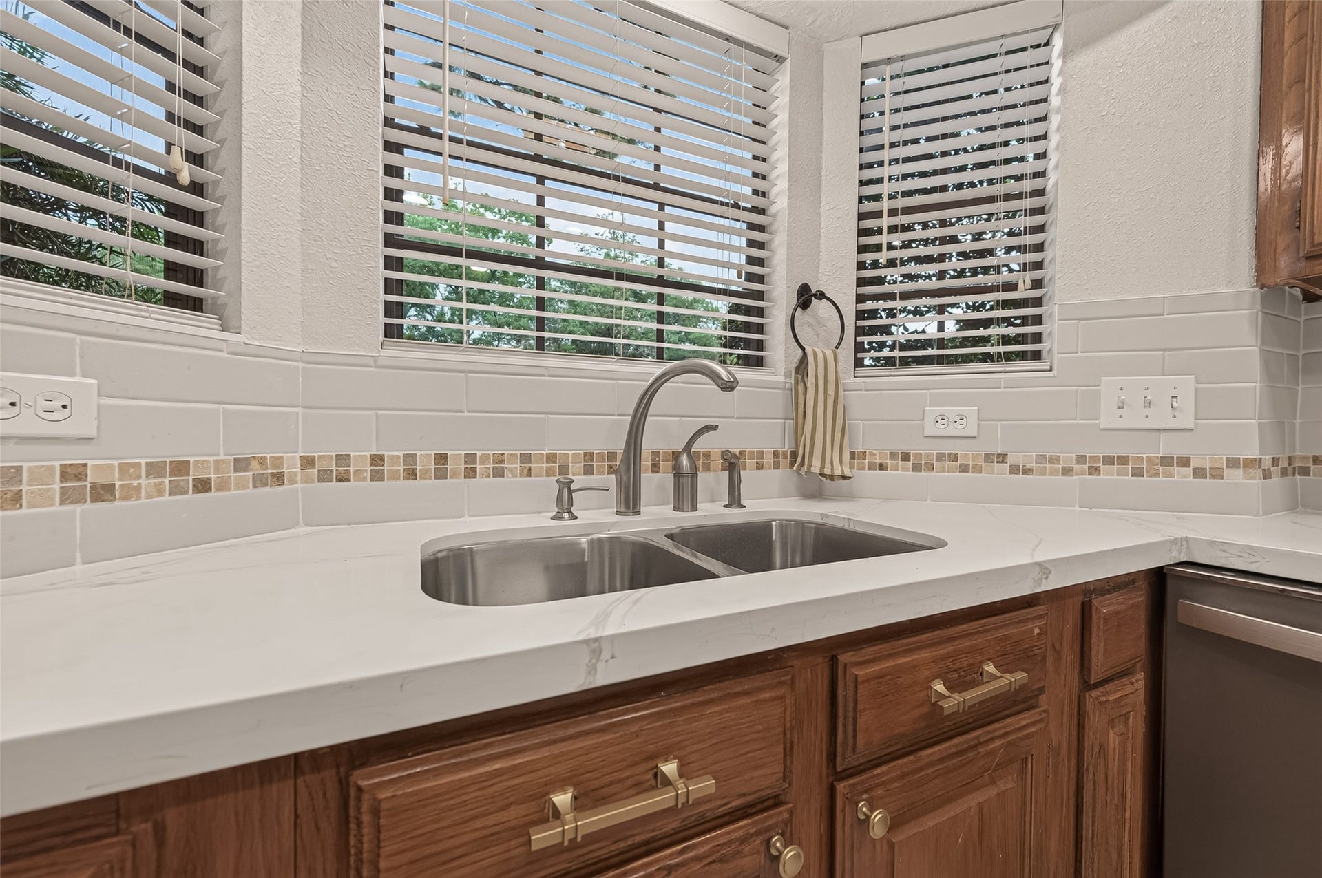 16405 Smith Street, Jersey Village, TX 77040 Framed by walls of windows, the sink area offers peaceful views of the front yard. From here, you'll enjoy watching neighbors on evening walks and children making their way home from schoolsimple moments that remind you why people love established neighborhoods. Updated in 2025, the quartz countertops, subway tile backsplash, and 50/50 stainless steel sink create a fresh, clean workspace that's as practical as it is attractive. Natural light makes everyday tasks just a little more enjoyable.