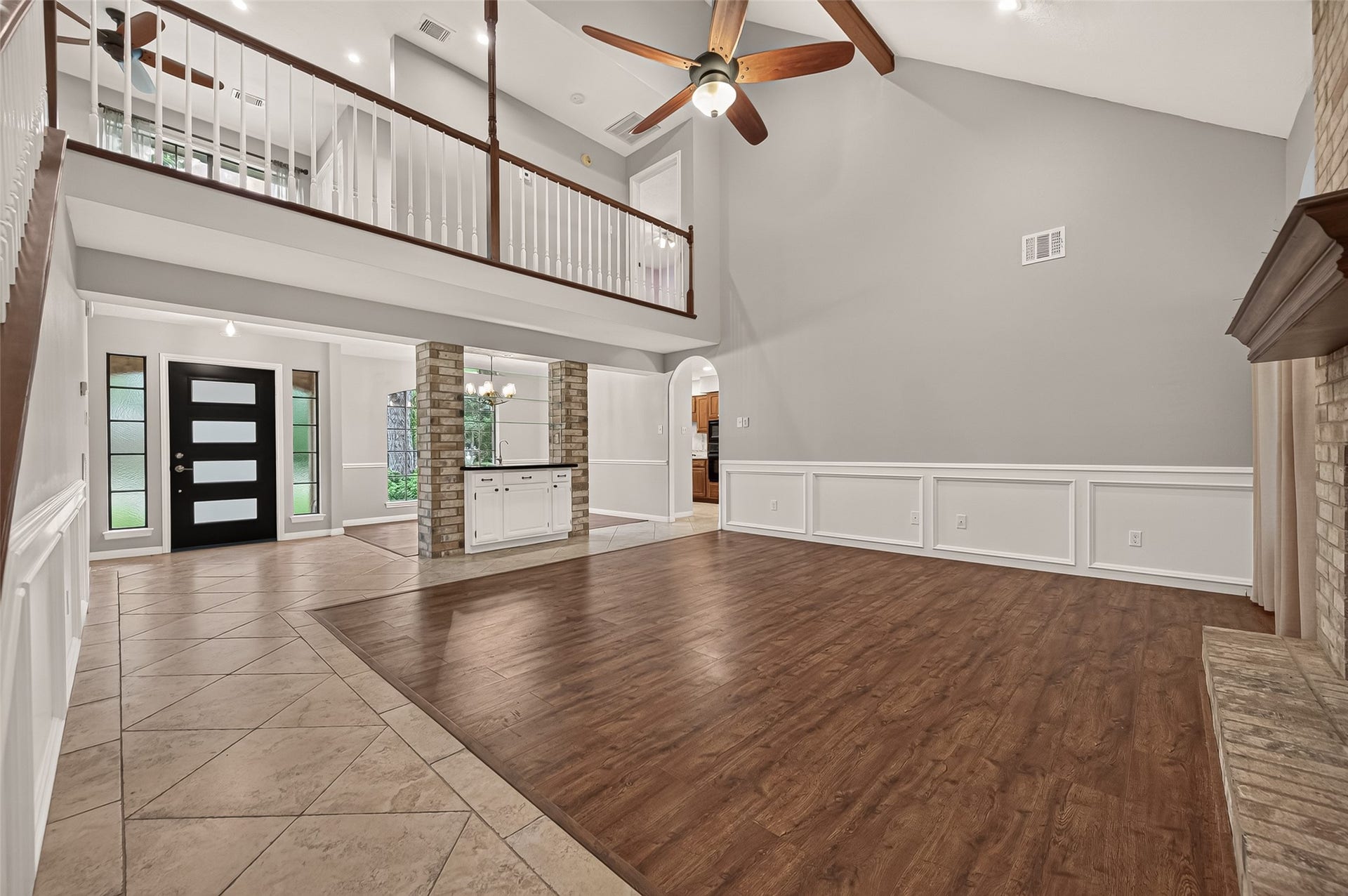 16405 Smith Street, Jersey Village, TX 77040 The heart of the home unfolds in this impressive family room, where soaring vaulted ceilings, exposed wood beams, and a dramatic second-story overlook create an immediate sense of openness. Rich wood-look flooring, recessed lighting, and a ceiling fan enhance both comfort and style, while the open design naturally brings family and friends together whether relaxing by the fireplace, entertaining guests, or simply enjoying everyday moments at home.