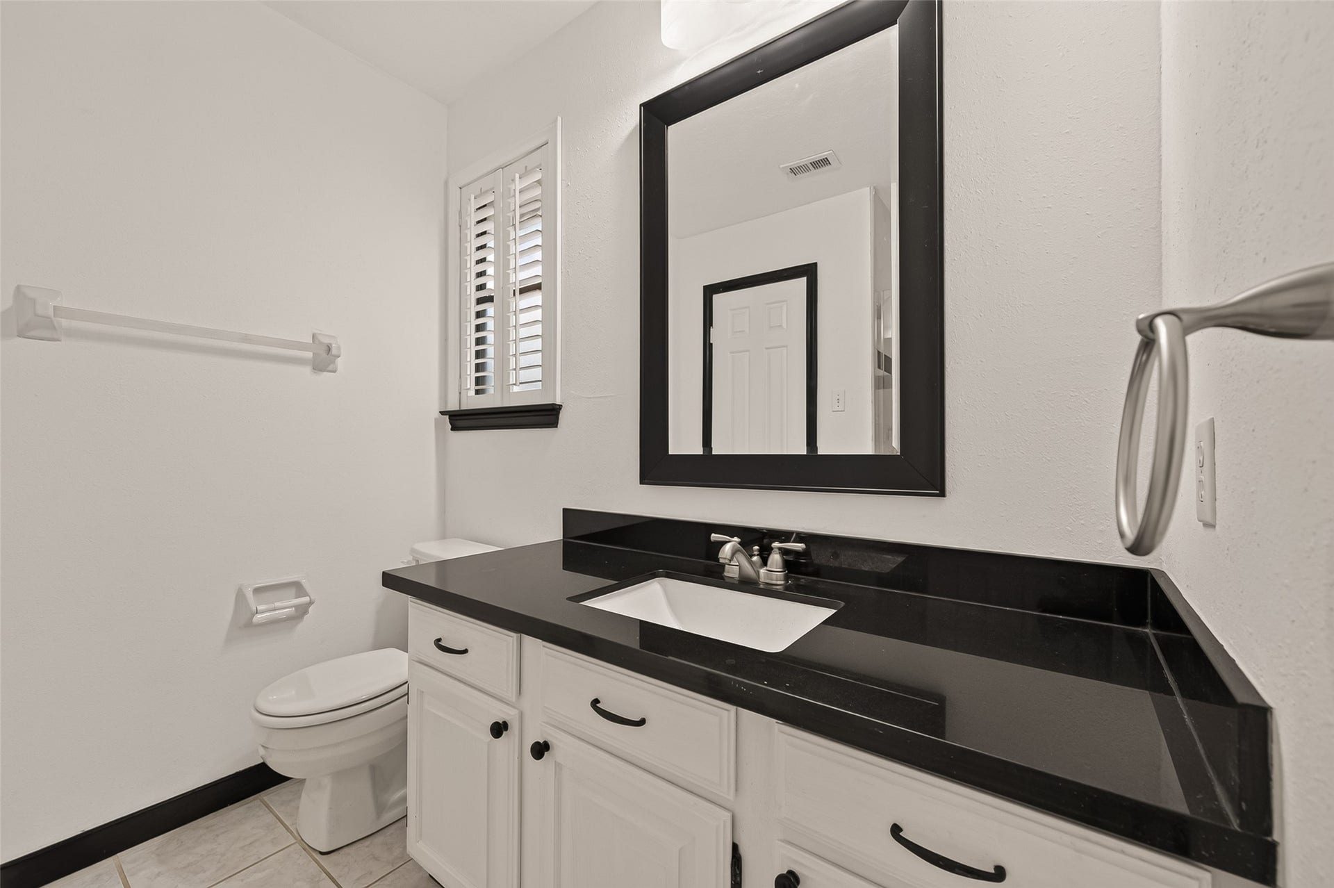 16405 Smith Street, Jersey Village, TX 77040 Bedroom #3 enjoys the convenience of its own private ensuite bath, creating a comfortable retreat for family members or overnight guests. The bath features a granite-topped vanity with an undermount sink, framed mirror, and a tiled walk-in shower with a glass door. A deep linen closet provides generous storage for towels and everyday essentials.