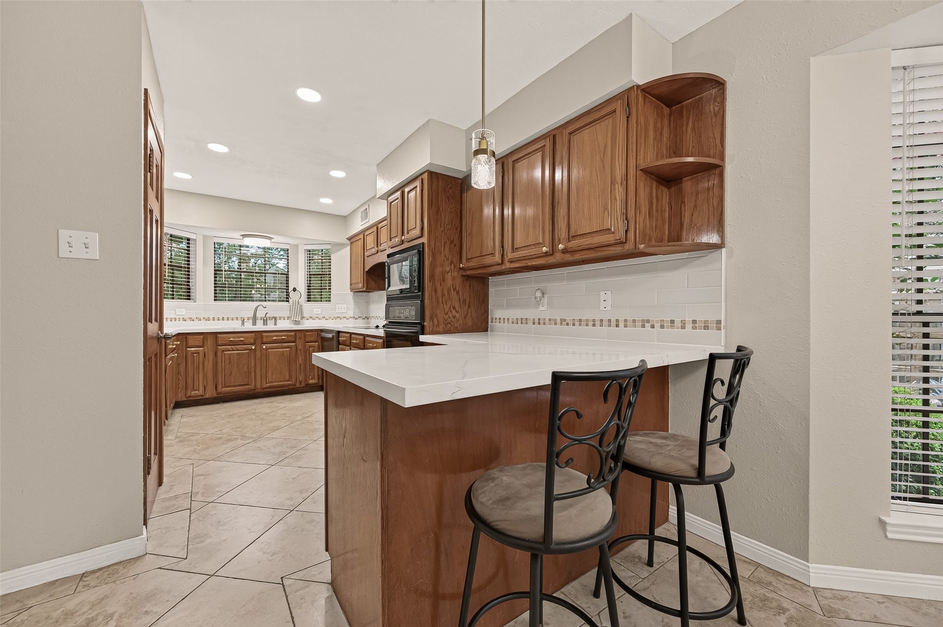 16405 Smith Street, Jersey Village, TX 77040 Some of life's best conversations happen in the kitchen, and this breakfast bar was made for them. Whether enjoying a quick breakfast, catching up over coffee, or serving a holiday buffet, the generous quartz countertop creates a natural gathering place while keeping everyone connected to the breakfast nook, kitchen, and family room. Pendant lighting adds warmth overhead, making this versatile space ideal for both everyday living and entertaining.