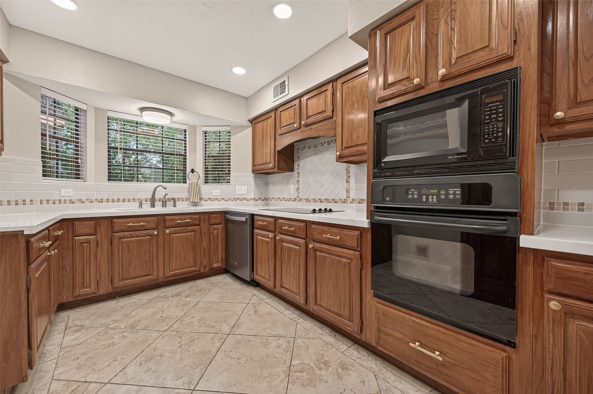 16405 Smith Street, Jersey Village, TX 77040 The heart of every home is the kitchen, and this one offers the perfect blend of warmth, functionality, and timeless style. Rich hardwood cabinetry pairs with quartz countertops, an updated subway tile backsplash, mosaic ribbon tile, and abundant workspace for everything from busy weekday breakfasts to preparing holiday feasts. Designed for both efficiency and entertaining, the thoughtful layout keeps family and friends connected while everything you need remains within easy reach.