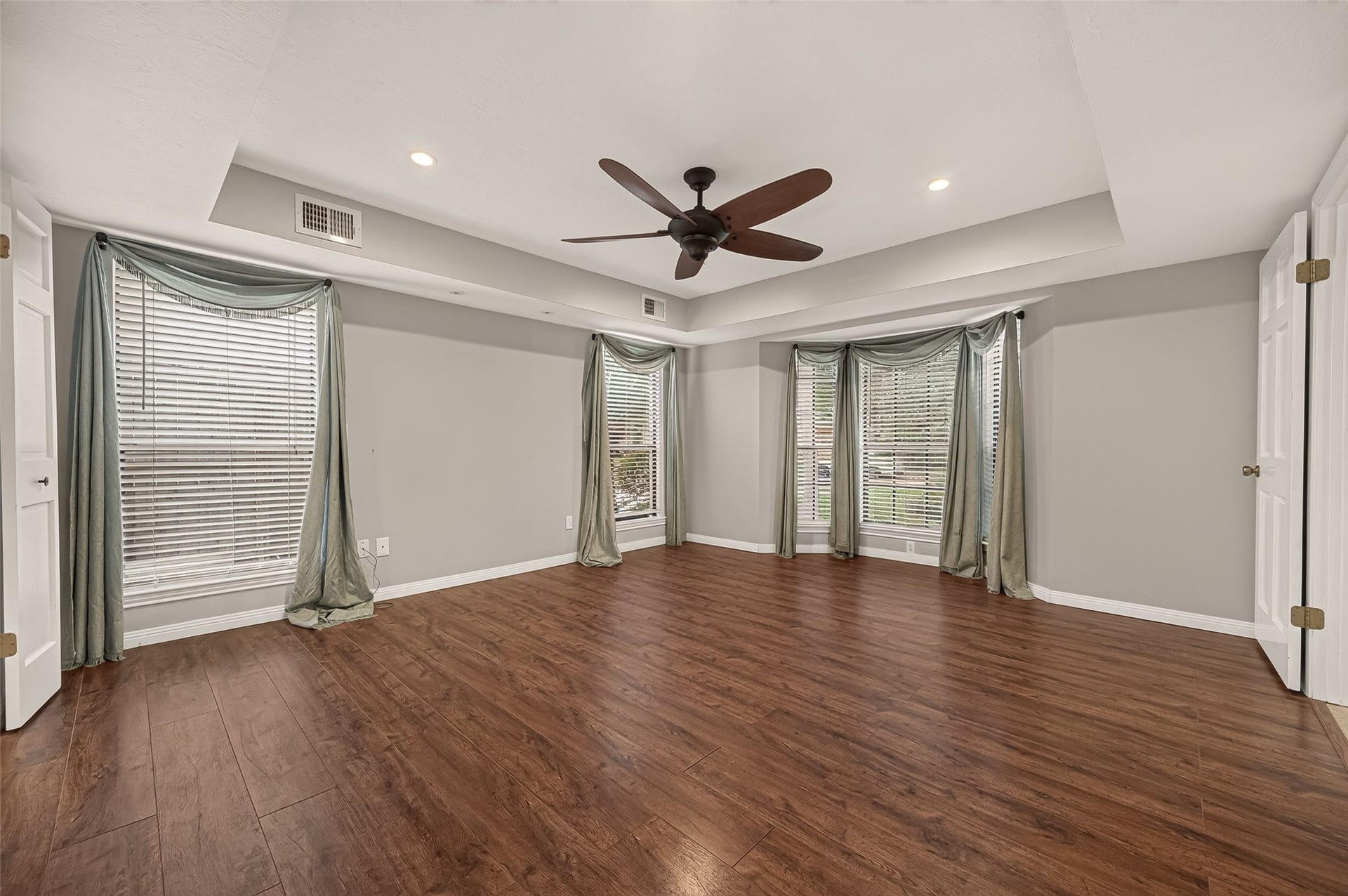 16405 Smith Street, Jersey Village, TX 77040 The spacious Primary Suite offers the perfect retreat at the end of the day. A striking coffered ceiling with recessed lighting, ceiling fan, and built-in reading lights adds architectural interest and everyday convenience. Multiple windows fill the room with natural light, while generous dimensions easily accommodate a king-size bedroom set and sitting area. Two lighted walk-in closets provide exceptional storage, while double doors open to the ensuite bath.