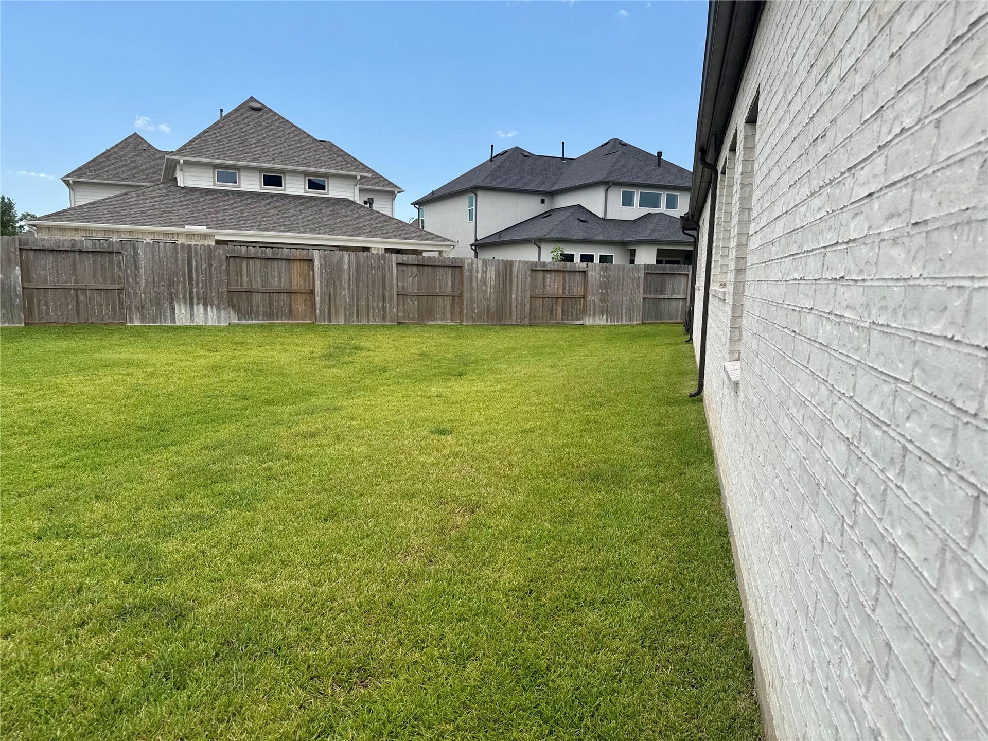 9911 Deep Water Drive, Missouri City, TX 77459 Expansive backyard with lush green lawn, bordered by a sturdy wooden fence for privacy, perfect for outdoor activities and relaxation.