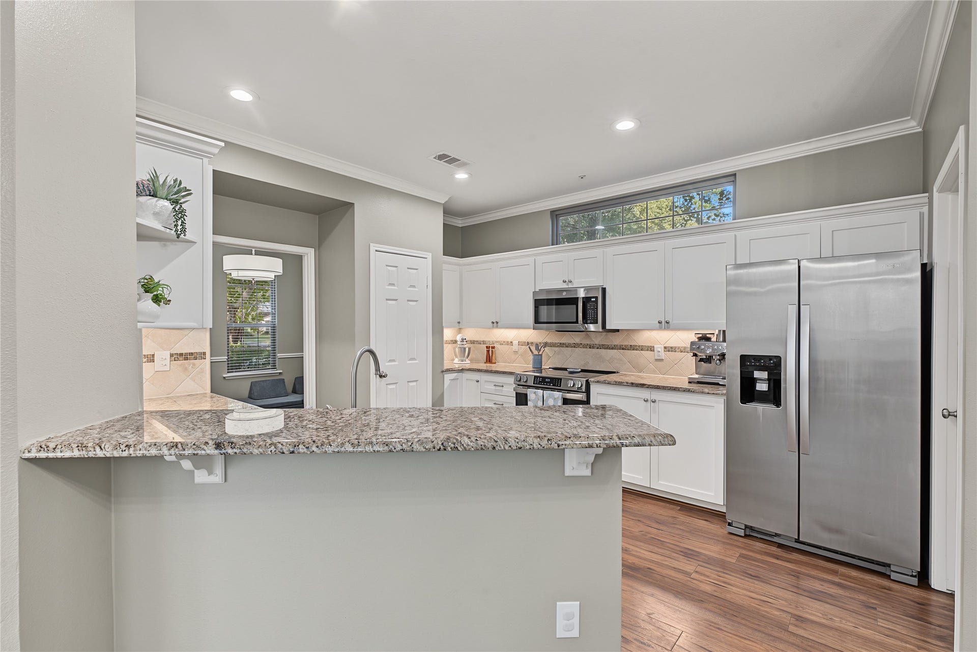 5 Otter Pond Place, The Woodlands, TX 77381 This kitchen features a breakfast bar, granite countertops, and an abundance of natural light.