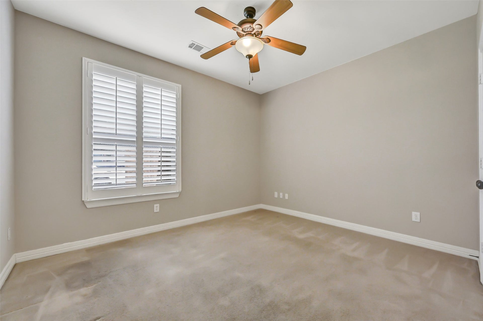 1813 Sandy Lake Drive, Friendswood, TX 77546 On one side of the home, this comfortable secondary bedroom features fresh neutral paint, a ceiling fan, plantation-shuttered window & double-door closet. Its location near the shared Jack & Jill bath creates a nicely separated secondary bedroom wing.