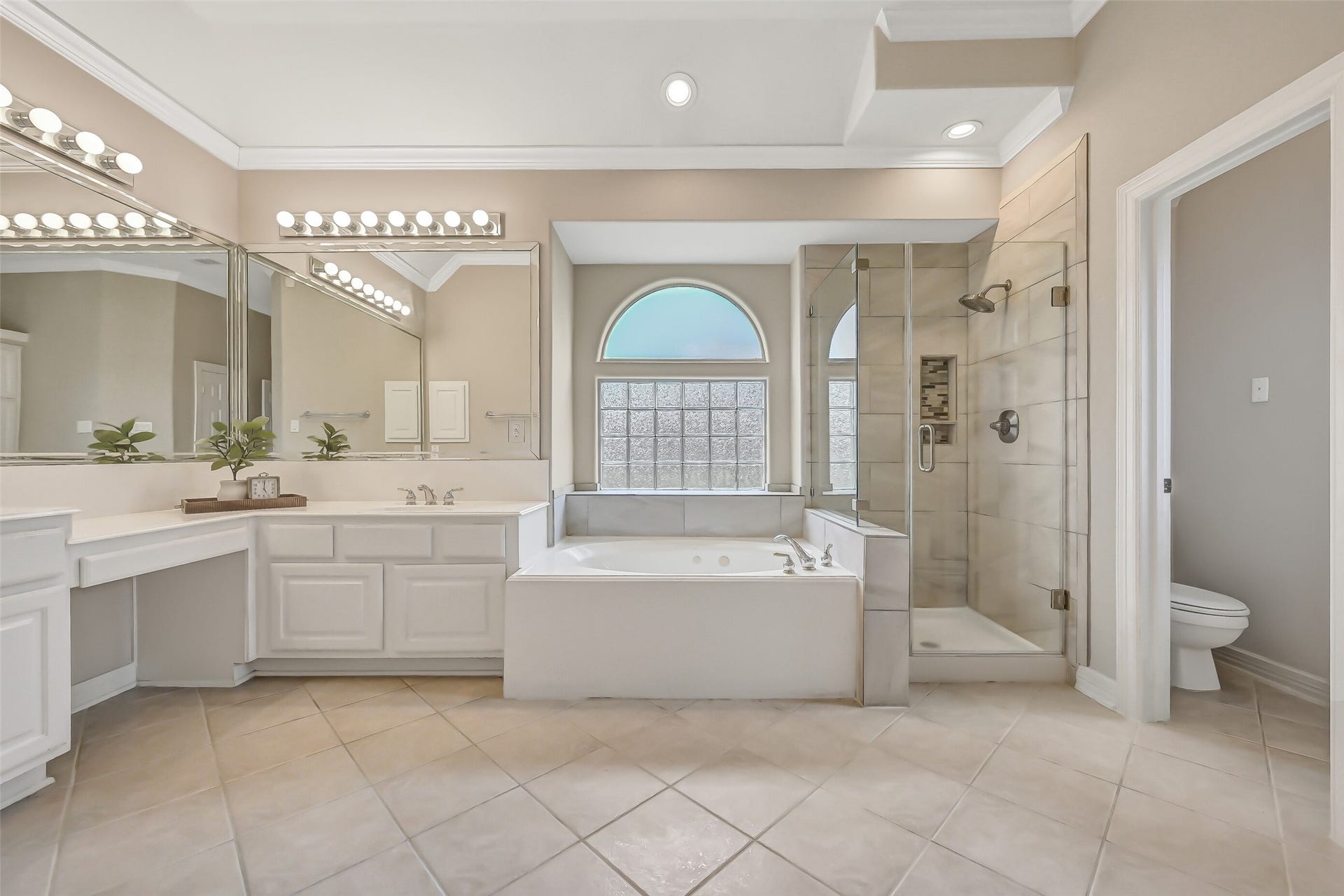 1813 Sandy Lake Drive, Friendswood, TX 77546 The renovated primary bath feels exceptionally spacious, featuring a jetted soaking tub beneath an impressive arched window, an oversized seamless-glass shower, separate vanity areas & a private water closet, all complemented by a raised ceiling and abundant natural light.
