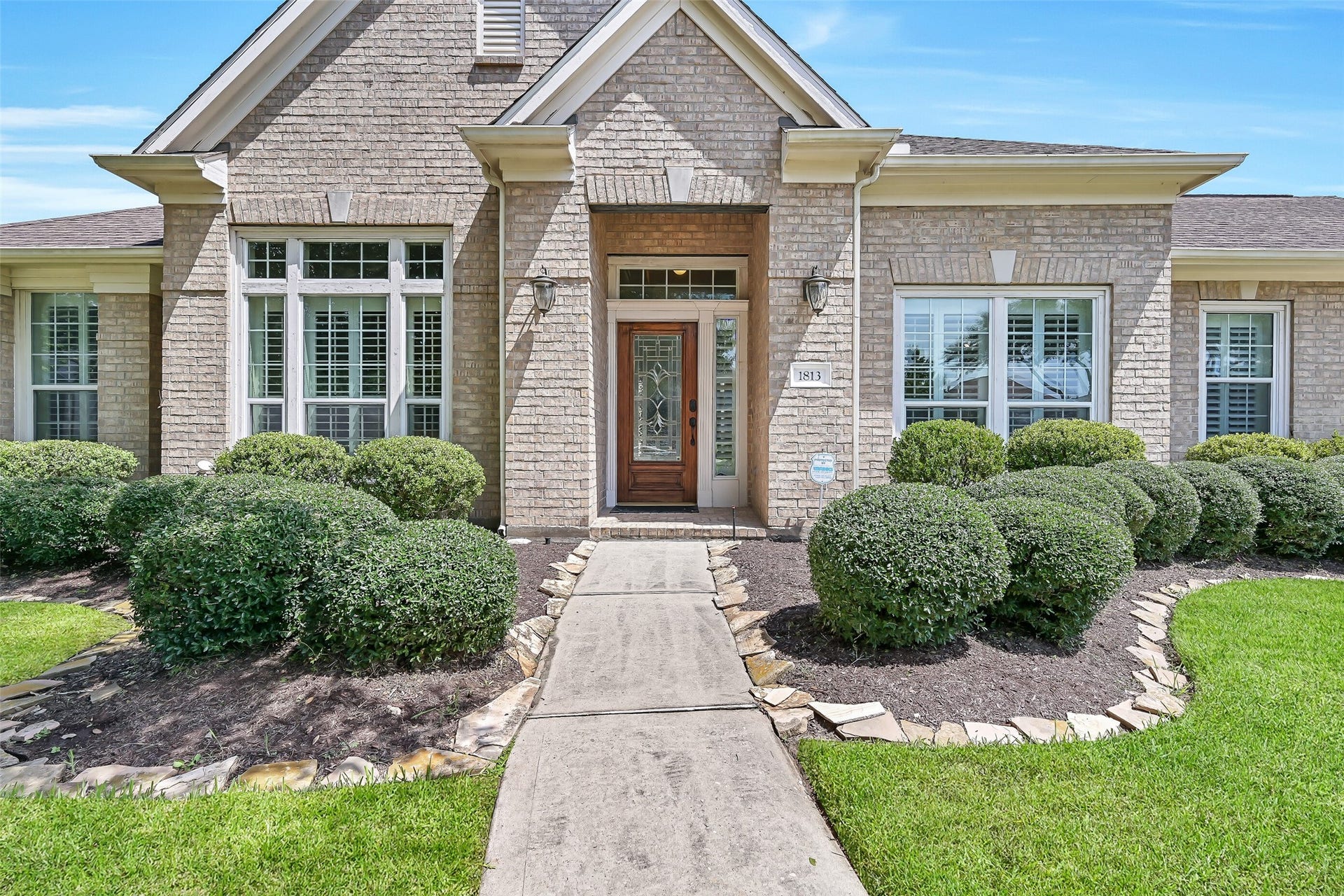 1813 Sandy Lake Drive, Friendswood, TX 77546 A closer look at the welcoming front entry reveals timeless brick architecture, mature manicured landscaping & an impressive combination of windows that brings abundant natural light into the home. Plantation shutters provide a polished look from both inside & out.