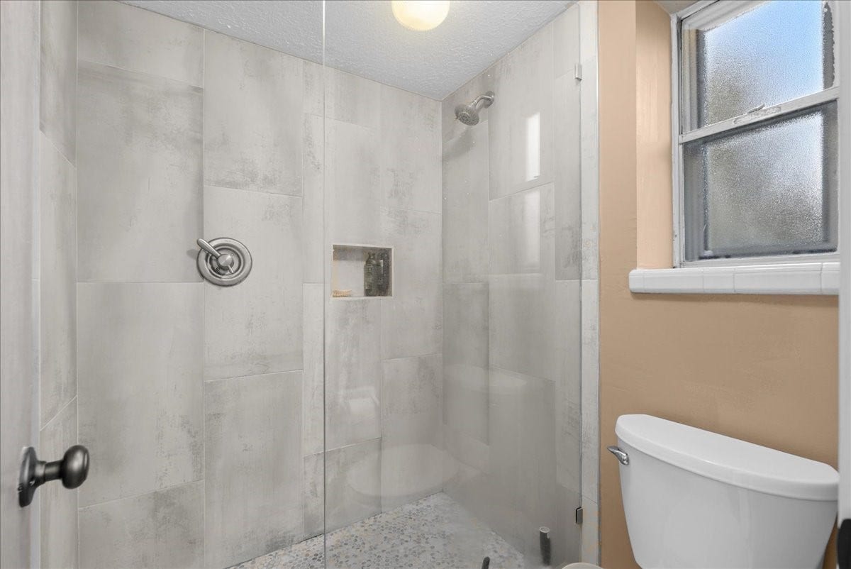 214 Oakwood Street, League City, TX 77573 Primary bathroom features a tiled walk-in shower with glass enclosure and recessed niche.