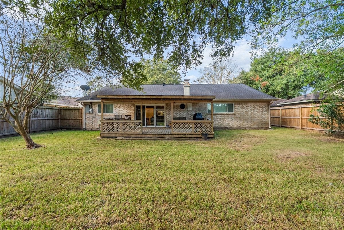 214 Oakwood Street, League City, TX 77573 Rear exterior showcasing the covered wood deck and generously sized fenced backyard.