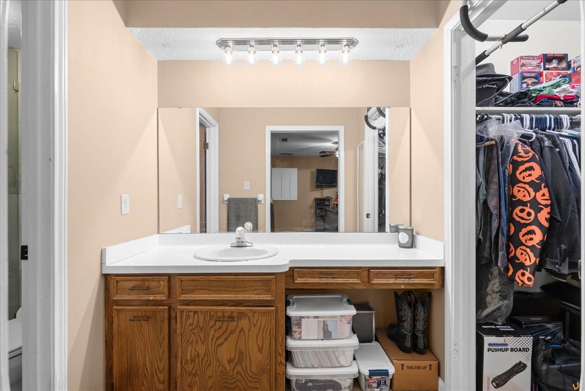 214 Oakwood Street, League City, TX 77573 Primary bathroom vanity with adjoining walk-in closet and shower area.