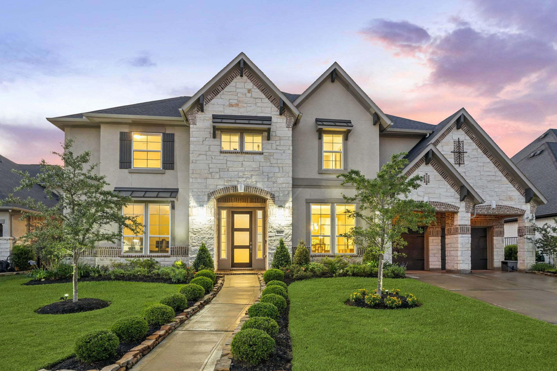 Stunning lakefront 2-story home features a beautiful stone and stucco exterior with tile roof. The manicured lawn and landscaped walkway lead to the elegant entrance.