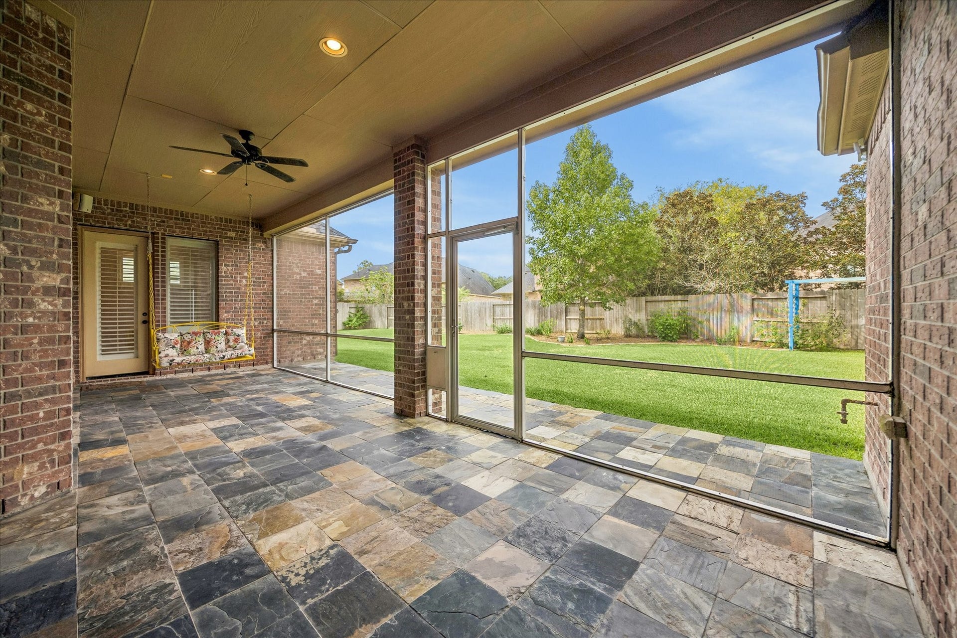 4506 Beacon View Court, Sugar Land, TX 77479 Spacious screened-in back porch with a beautiful slate-tile floor, ceiling fan, and charming porch swing overlooking the lush backyard.