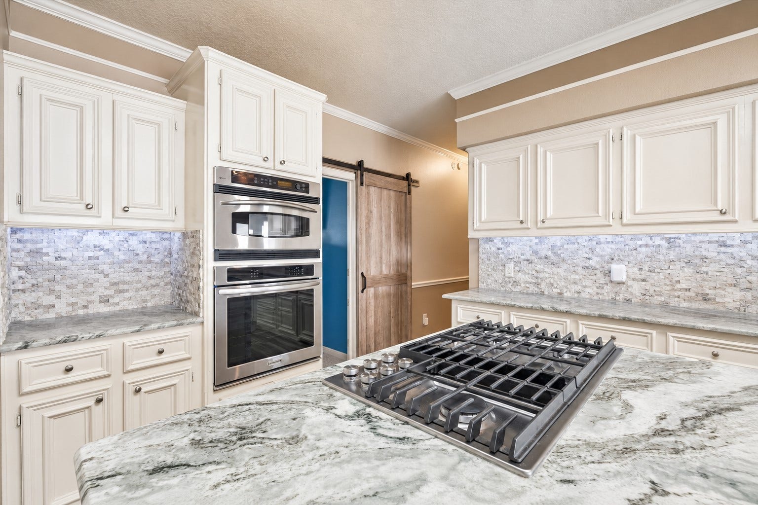 1331 EDWARDS DRIVE, Dickinson, TX 77539 THE KITCHEN INCLUDES DOUBLE WALL OVENS, A LARGE GAS COOKTOP, GENEROUS PREP SPACE, AND A SLIDING BARN DOOR LEADING TO THE ADJOINING AREA.