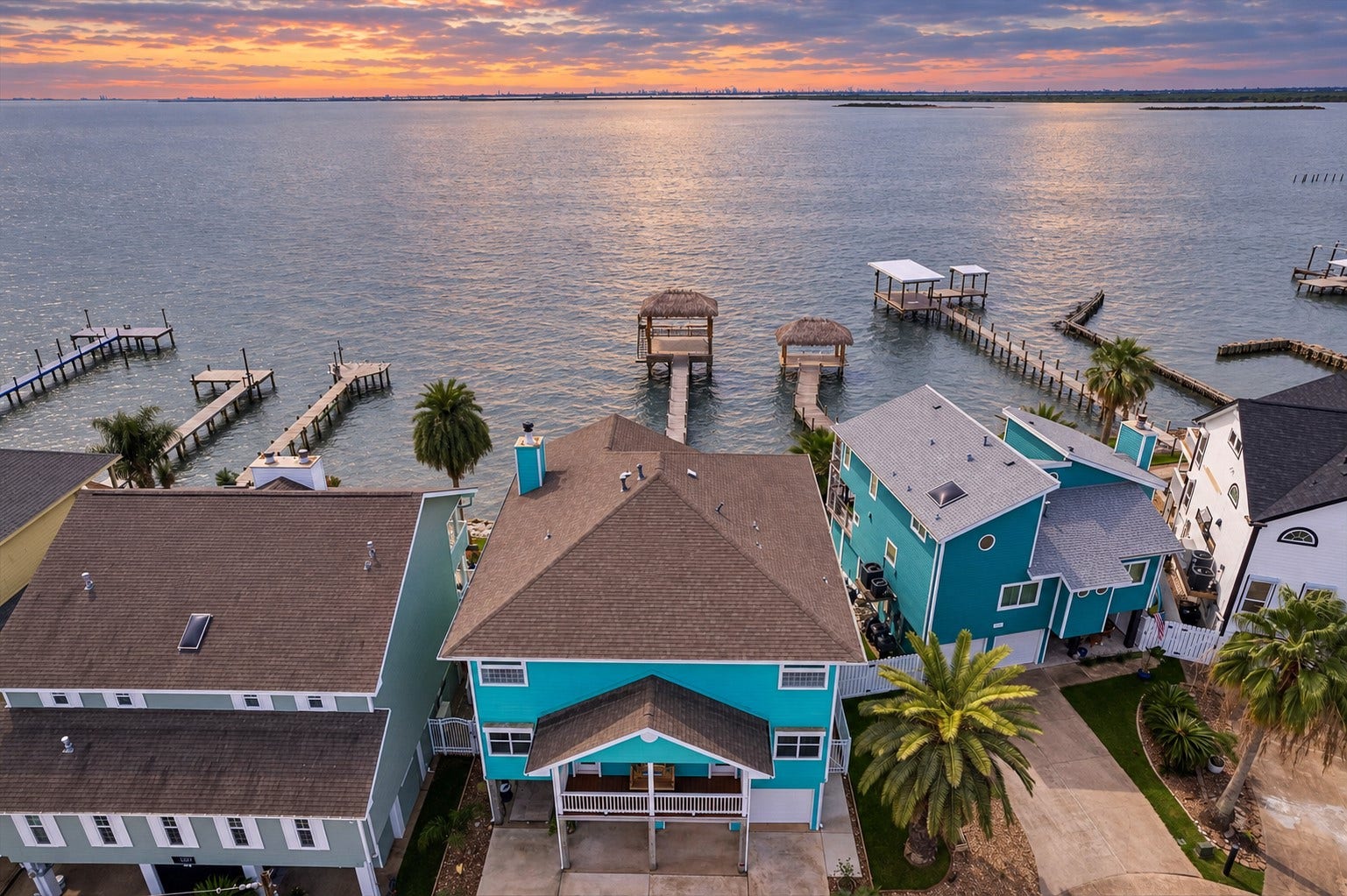 1331 EDWARDS DRIVE, Dickinson, TX 77539 EXPANSIVE AERIAL VIEW HIGHLIGHTING THE WATERFRONT SETTING, PRIVATE PIERS, AND MULTIPLE COVERED PALAPA AREAS. THE OPEN BLUE-GRAY WATER AND DISTANT HORIZON EMPHASIZE THE PROPERTYS DIRECT BAY ACCESS.