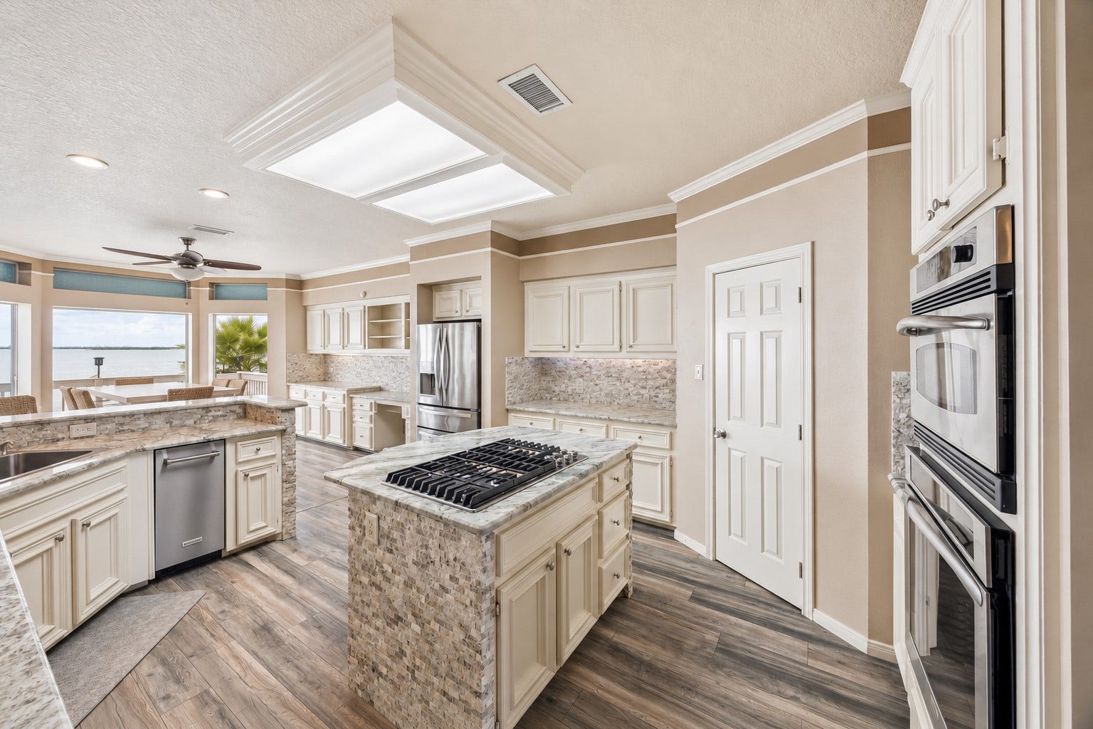 1331 EDWARDS DRIVE, Dickinson, TX 77539 THIS WIDE KITCHEN VIEW HIGHLIGHTS MULTIPLE WORK ZONES, SUBSTANTIAL STORAGE, AND LARGE WINDOWS SHOWCASING THE WATERFRONT SETTING.