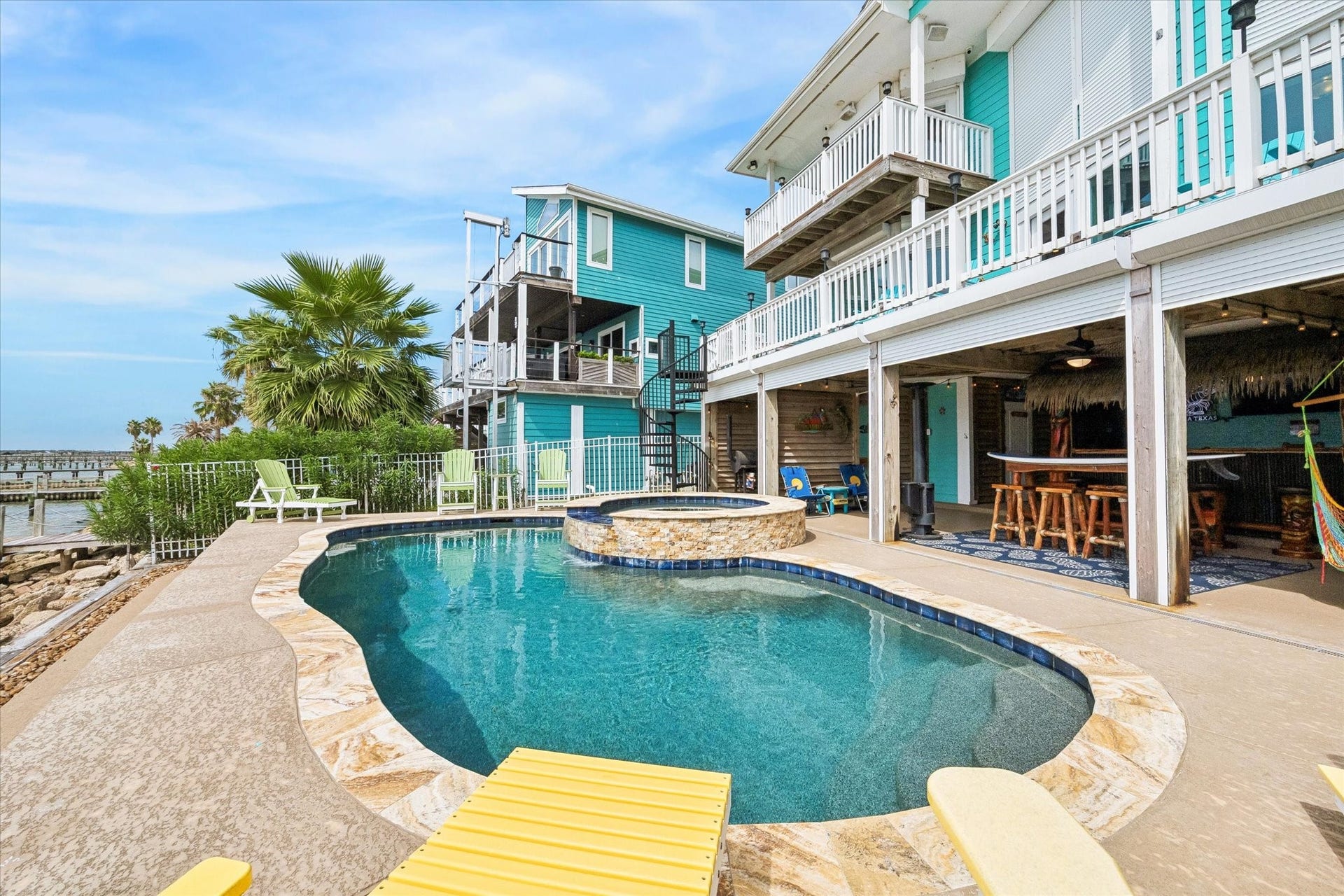 1331 EDWARDS DRIVE, Dickinson, TX 77539 THE REAR EXTERIOR FEATURES MULTIPLE BALCONIES, A SPIRAL STAIRCASE, A COVERED PATIO, AND A WATERFRONT POOL AND SPA.