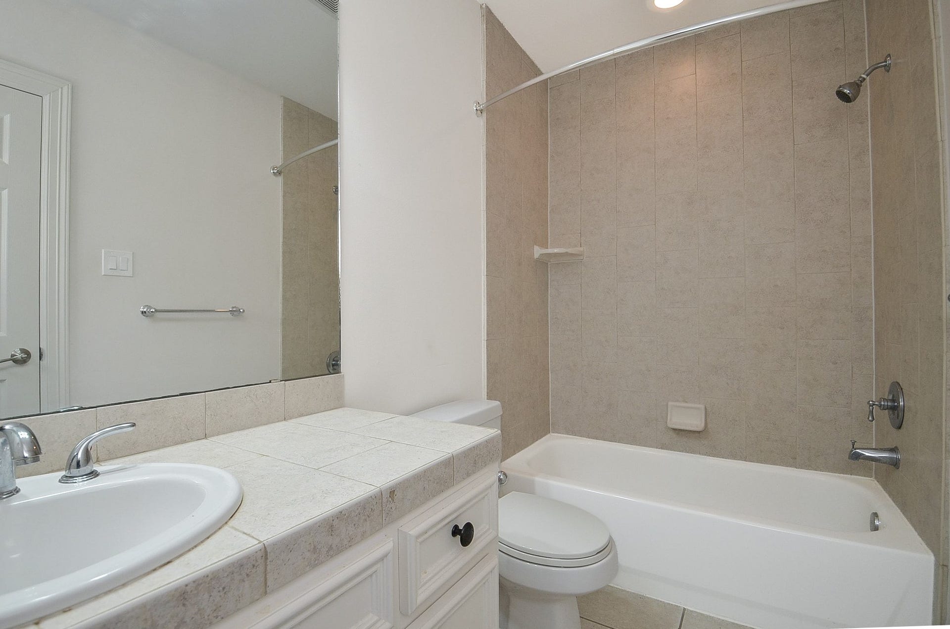 Full bathroom featuring a tiled shower and tub combo, complemented by a classic vanity with ample counter space and a large mirror.