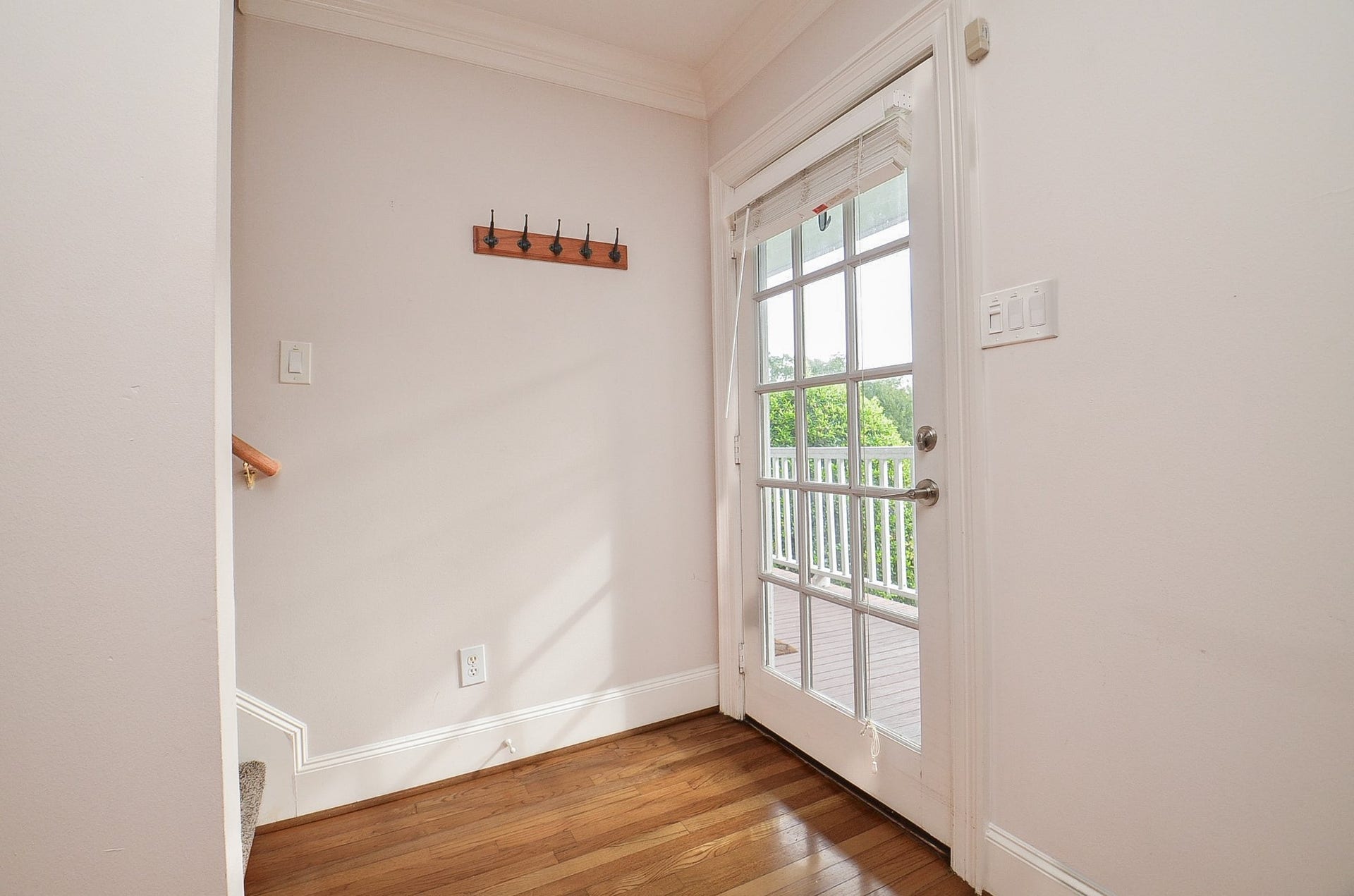 Bright entryway featuring elegant hardwood floors. Blinds are on all windows to provide privacy.