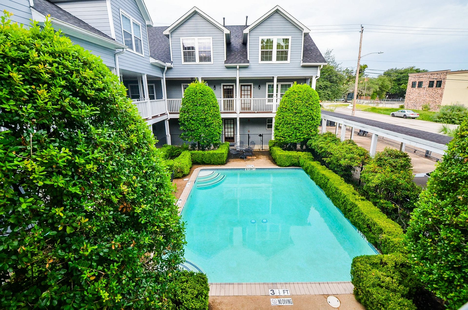 Charming condo community with a pool surrounded by lush greenery, perfect for relaxation and outdoor enjoyment.