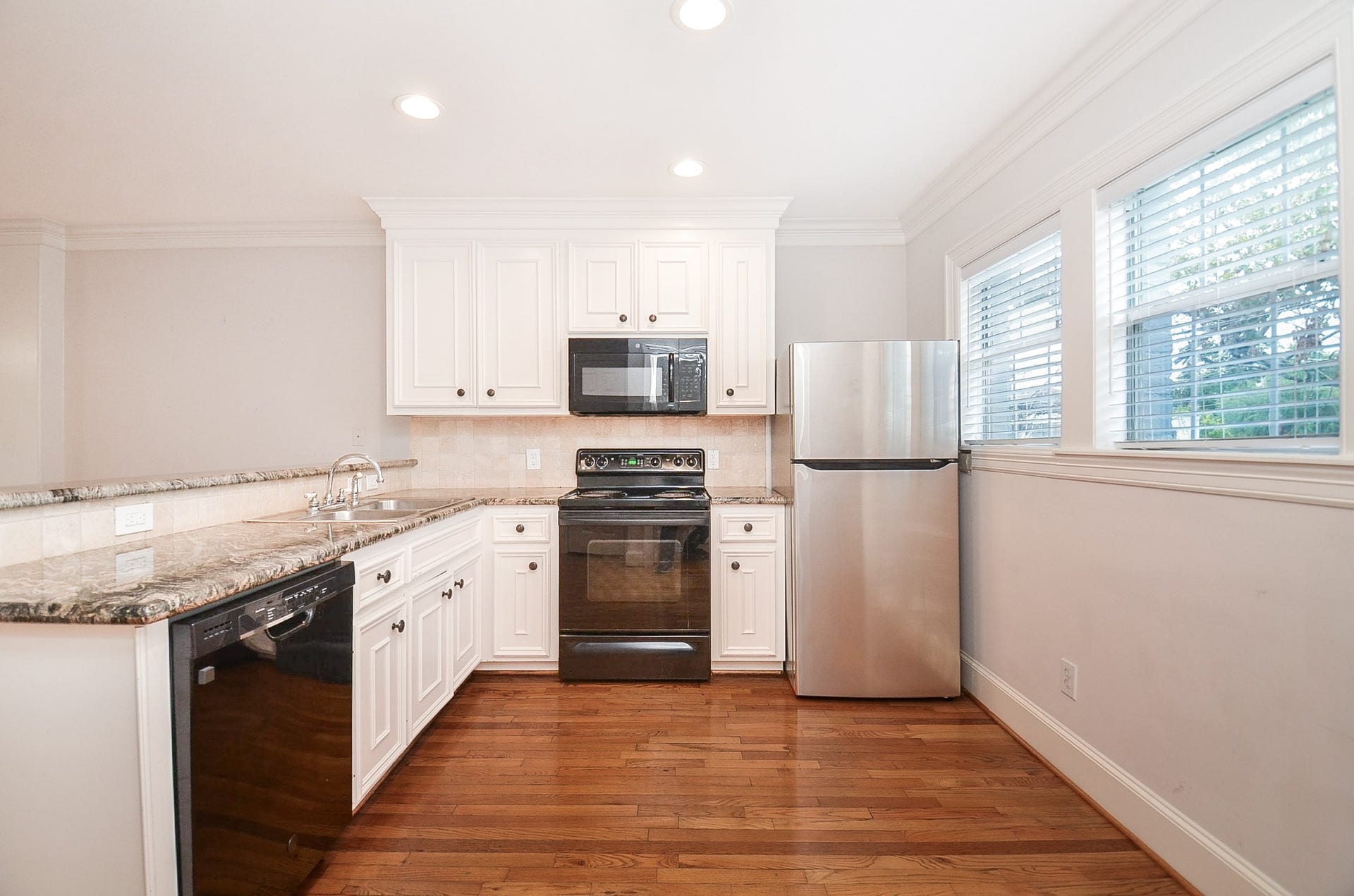 Bright kitchen with elegant granite countertops, appliances, and ample cabinetry, complemented by a wall of windows for natural light.