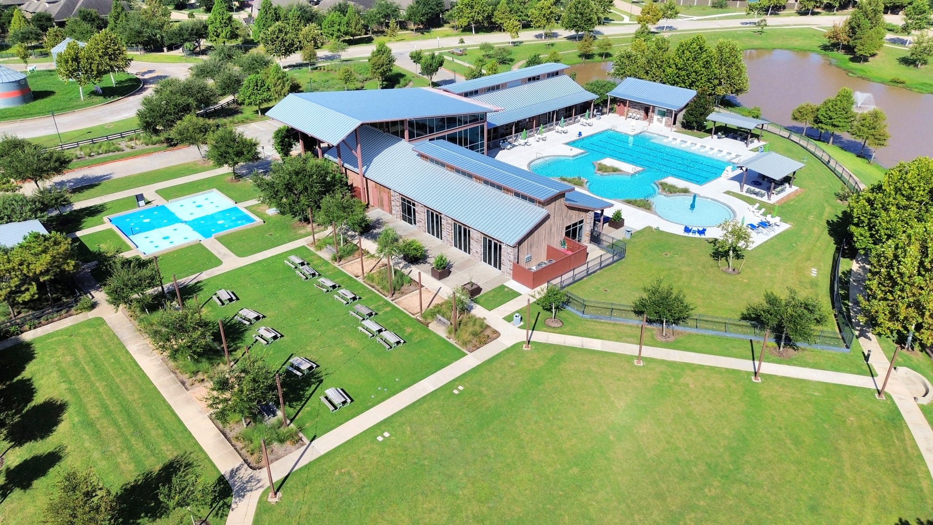 1423 Hackberry Heights Drive, Richmond, TX 77406 Stunning community center featuring a large swimming complex, lush green spaces, and scenic pond views, perfect for recreation and relaxation.