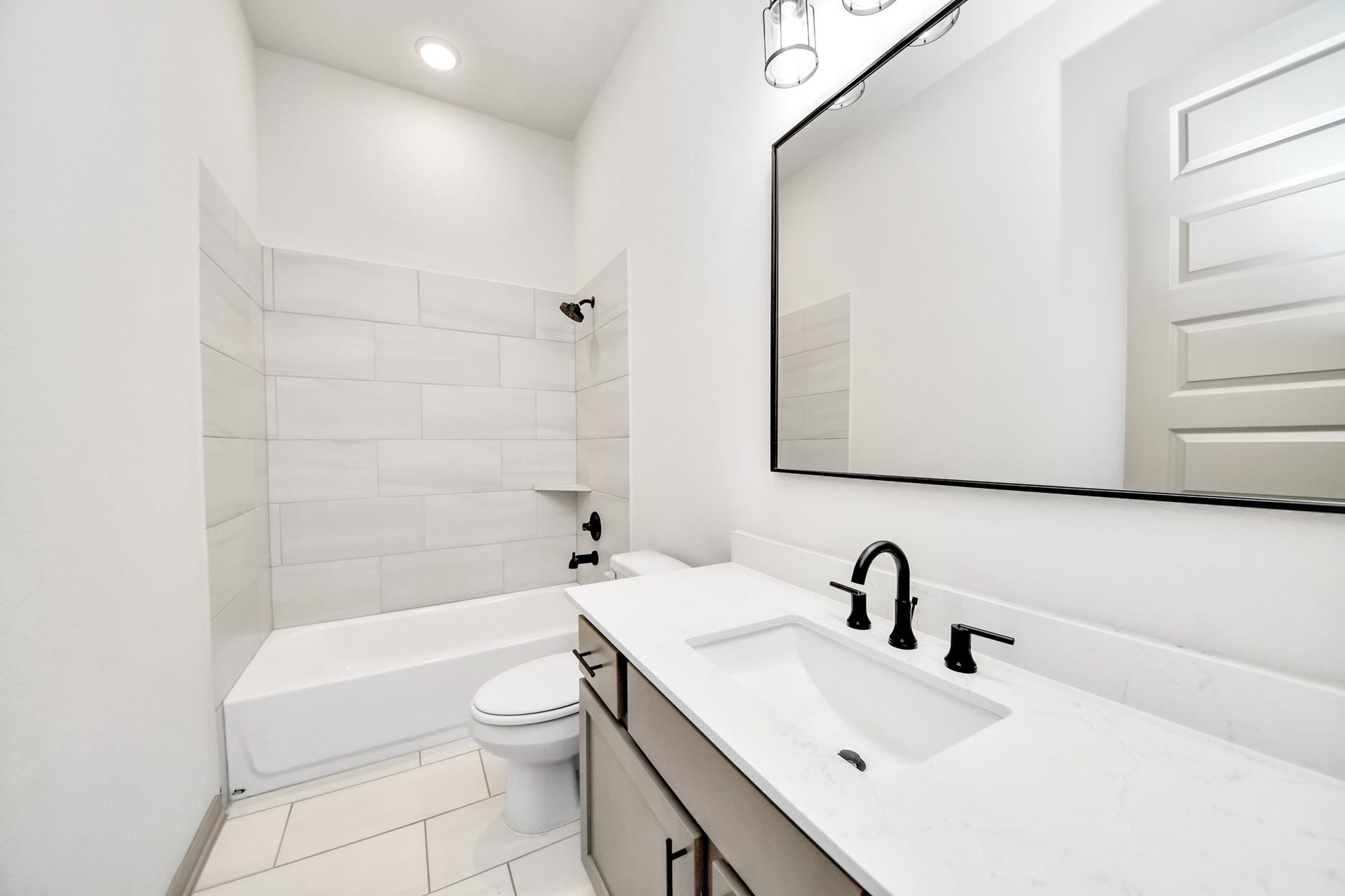 1423 Hackberry Heights Drive, Richmond, TX 77406 Sleek bathroom featuring a modern vanity with a large mirror, elegant black fixtures, and a pristine shower-tub combo with stylish tilework.