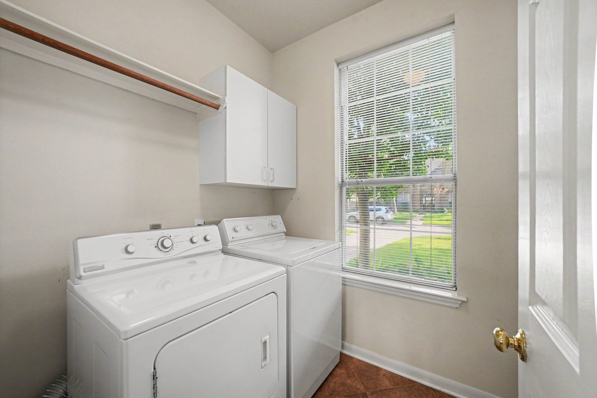 17510 Tall Maple Court, Houston, TX 77095 The first-floor laundry room features a full-size washer and dryer, overhead cabinetry, and additional shelving for storage and organization. A large window fills the space with natural light, making everyday laundry tasks a little brighter!