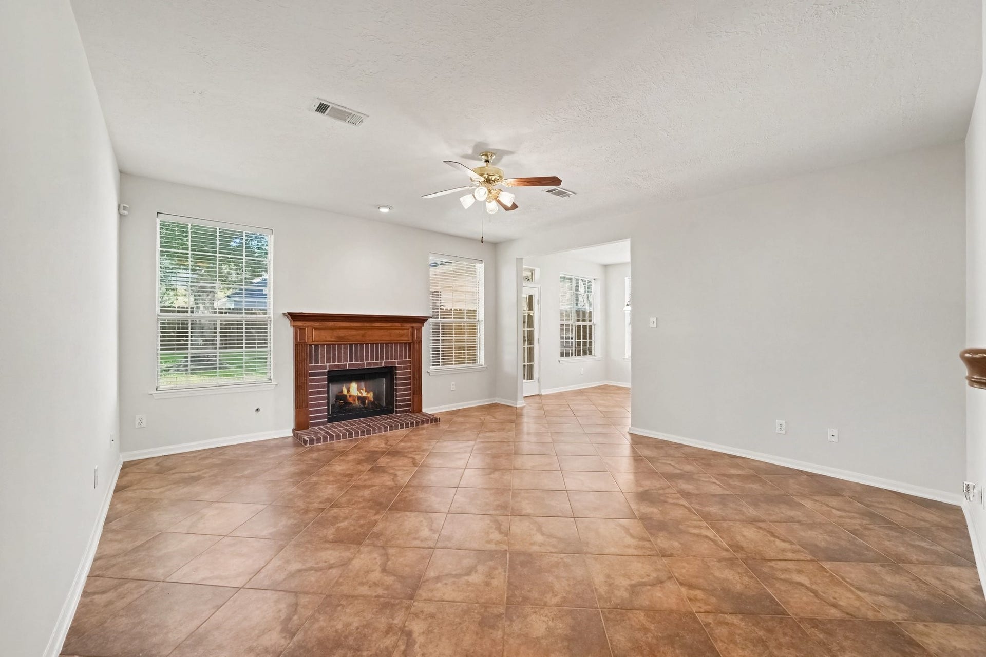 17510 Tall Maple Court, Houston, TX 77095 The inviting living room features a beautiful brick fireplace with wood mantel and gas logs. Oversized tile flooring, plenty of natural light, and an open layout create a welcoming space that flows seamlessly into the adjoining breakfast area and kitchen.