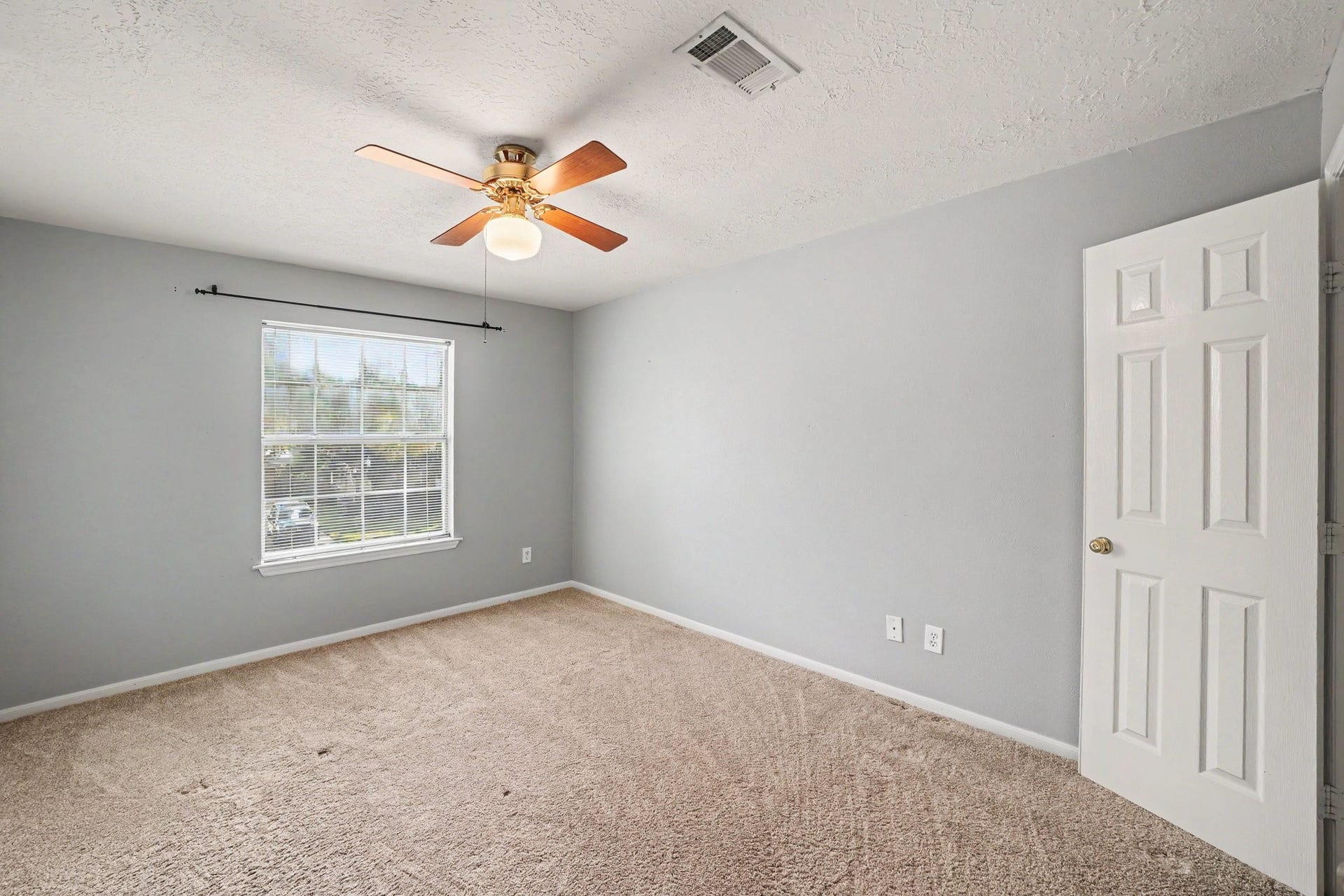 17510 Tall Maple Court, Houston, TX 77095 Another upstairs secondary bedroom features soft gray walls, plush carpeting, a ceiling fan, and a large window that brings in plenty of natural light. The neutral finishes and comfortable layout create a welcoming space for family or guests.