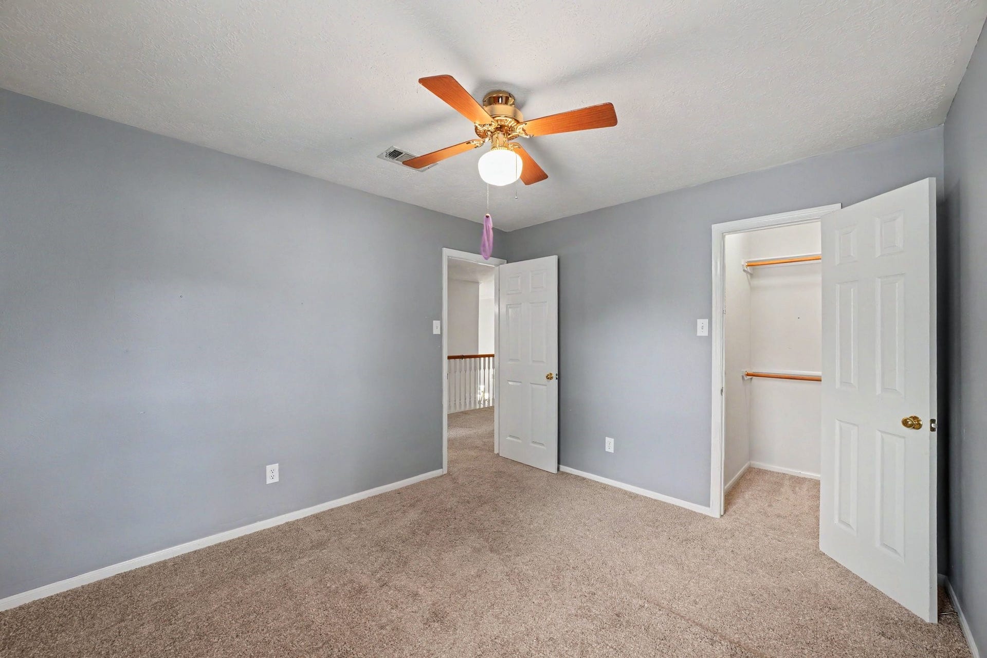 17510 Tall Maple Court, Houston, TX 77095 A second view of the upstairs secondary bedroom highlights the soft gray walls, plush carpeting, and walk-in closet with built-in shelving and hanging space, offering convenient storage and organization.
