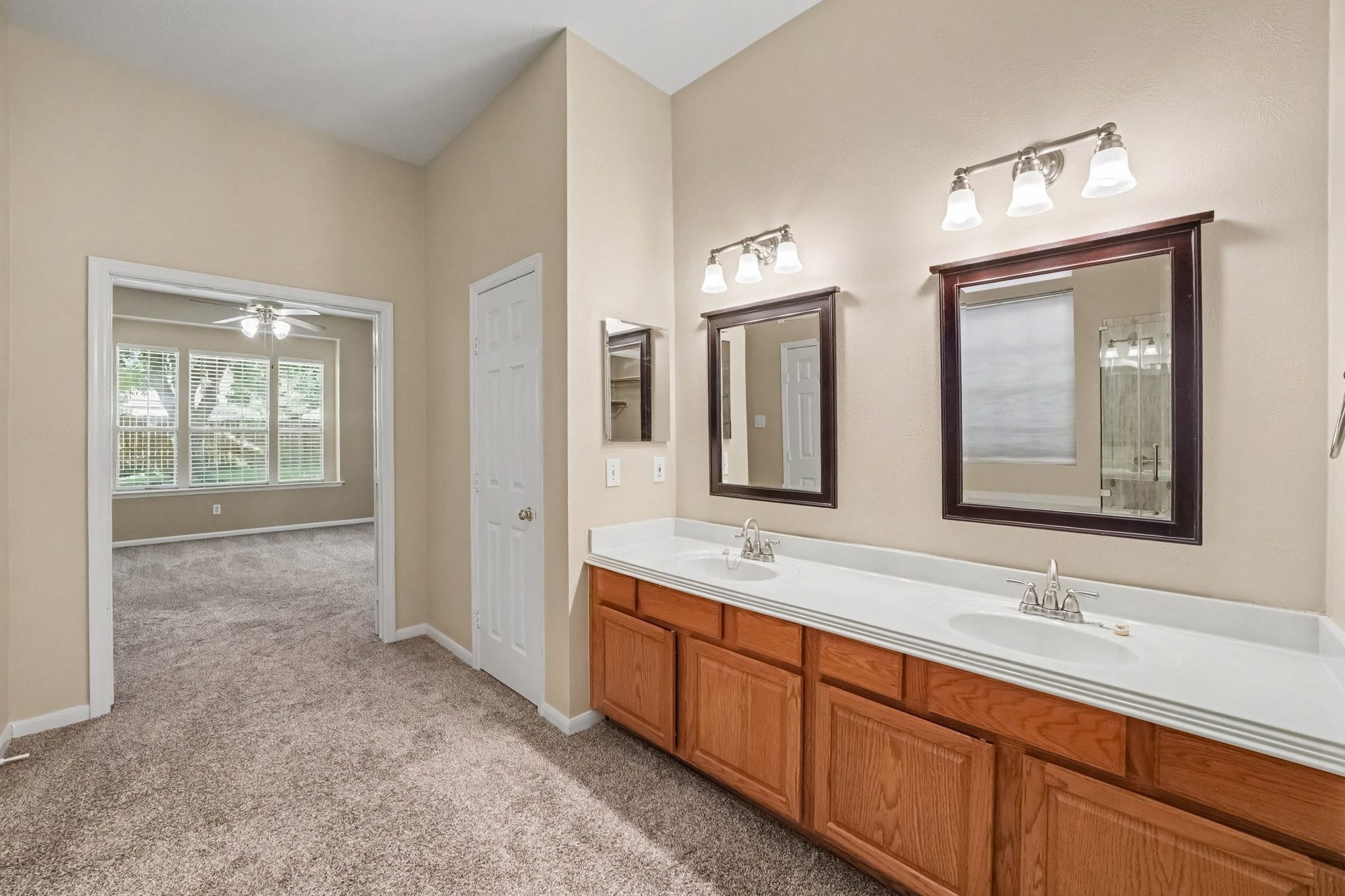 17510 Tall Maple Court, Houston, TX 77095 A second view of the primary bathroom highlights the extended double-sink vanity with individual framed mirrors, ample counter space, and generous cabinet storage. The open layout provides convenient access to the adjoining primary bedroom.