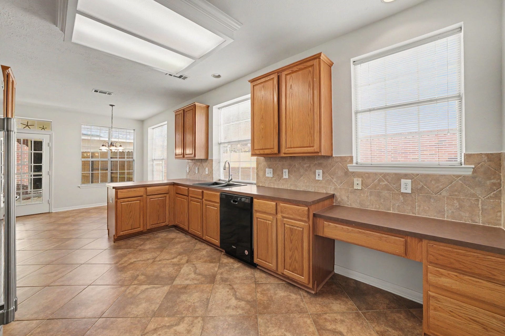 17510 Tall Maple Court, Houston, TX 77095 Another view of the kitchen highlights the convenient built-in desk area, abundant cabinetry and counter space, and natural light throughout. The adjoining breakfast area is surrounded by windows, creating a bright and inviting space for casual dining.