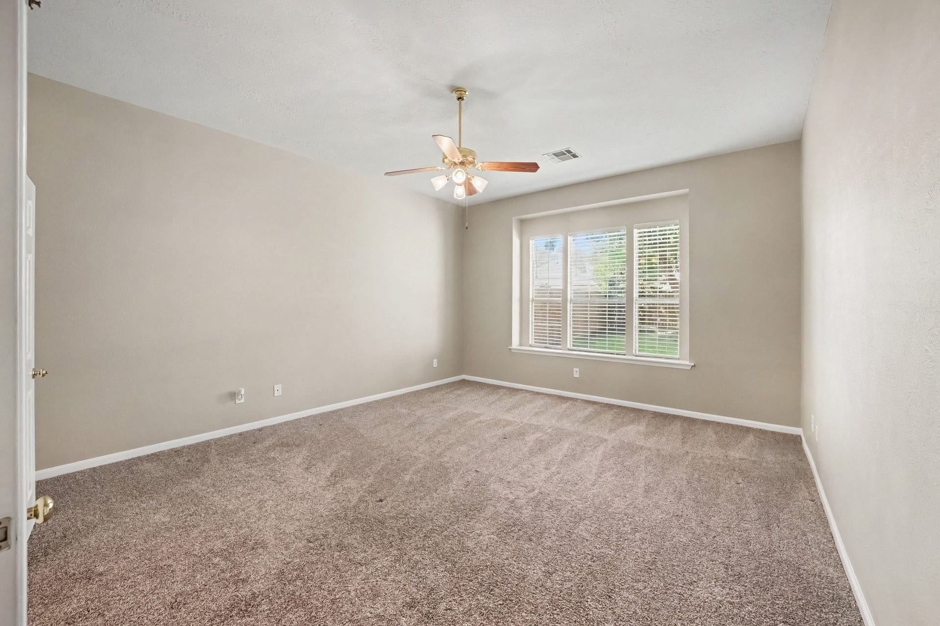 17510 Tall Maple Court, Houston, TX 77095 Another view of the spacious primary bedroom highlights the beautiful wall of windows overlooking the backyard, allowing plenty of natural light to fill the space. High ceilings and generous dimensions create an airy, comfortable retreat.