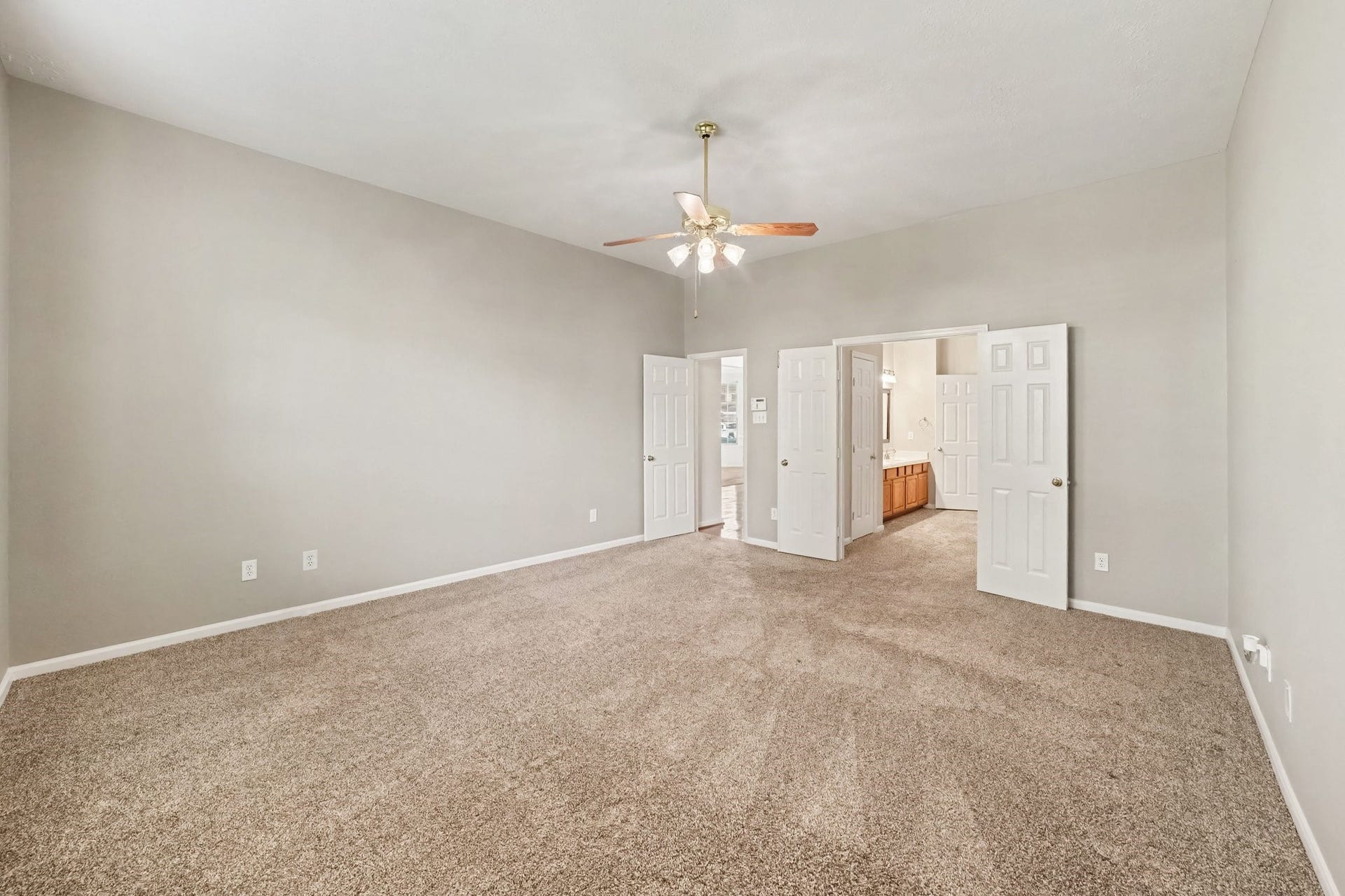 17510 Tall Maple Court, Houston, TX 77095 A second view of the primary suite showcases the high ceilings, generous floor space, and neutral finishes, with plenty of room for larger bedroom furnishings. Double doors lead into the private en-suite bathroom.