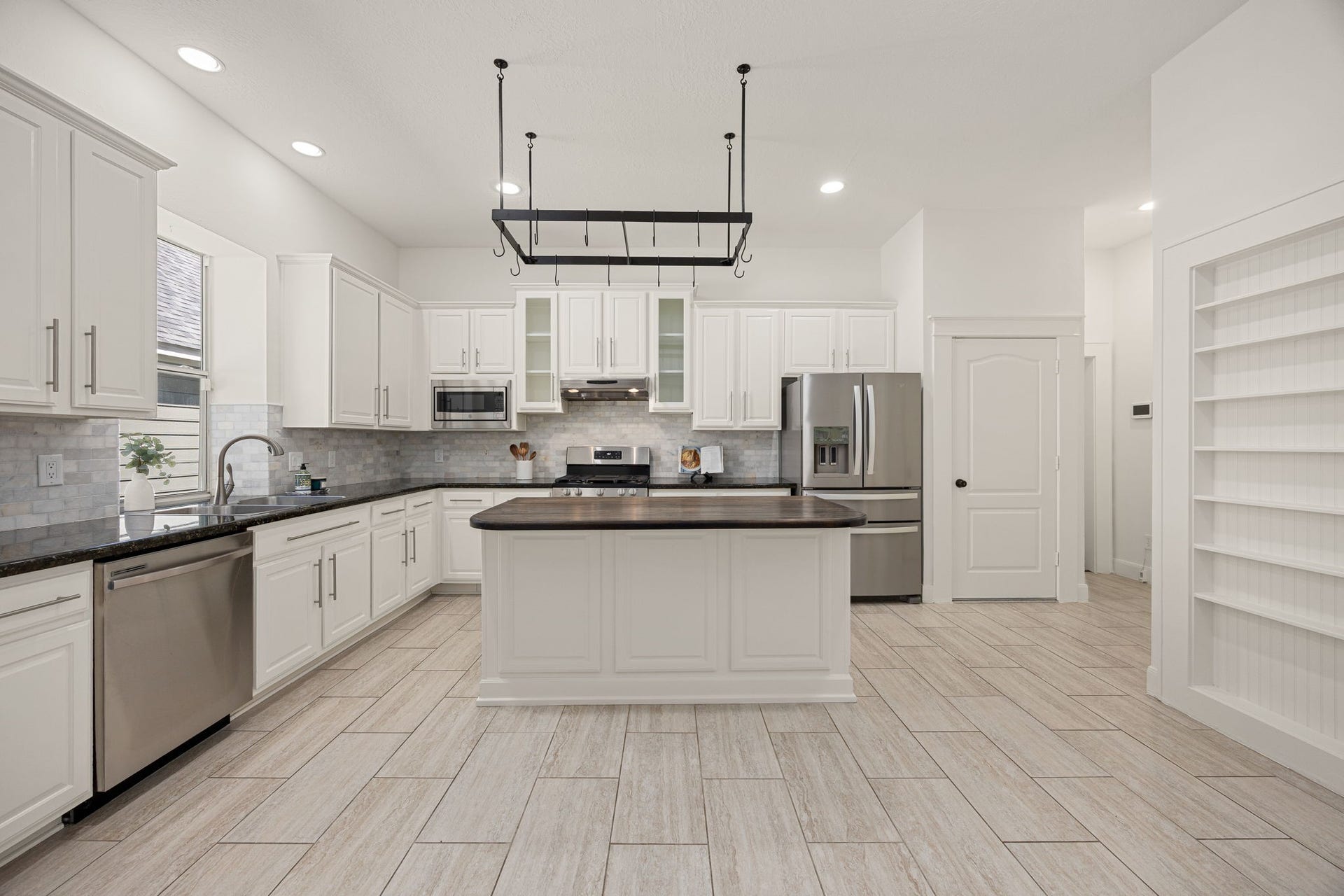 23 Pipers Meadow Street, The Woodlands, TX 77382 The heart of the home. Cook and entertain with ease in this well-appointed kitchen, offering an abundance of counter space, tile flooring, bright window, and built-in shelving.