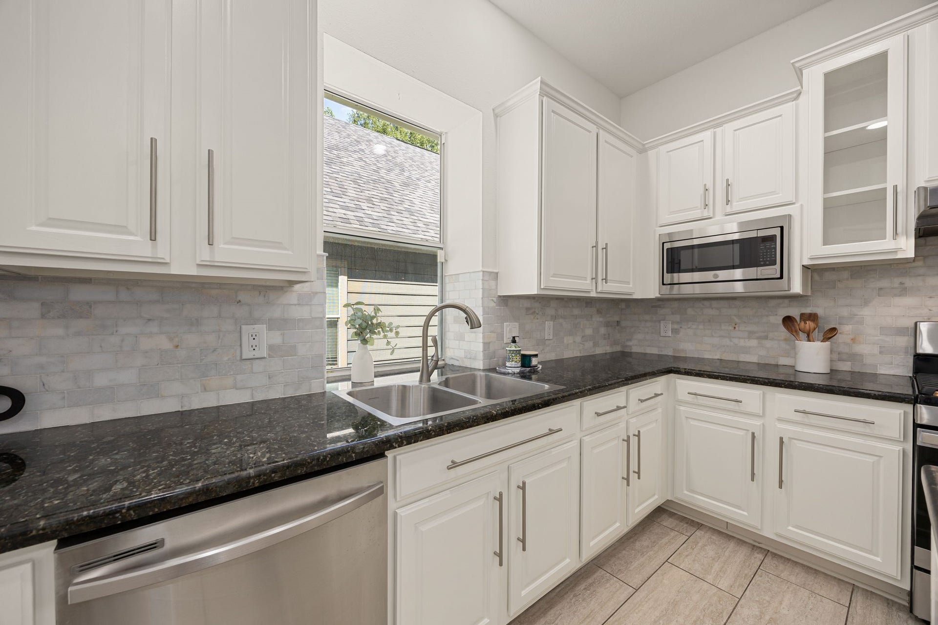 23 Pipers Meadow Street, The Woodlands, TX 77382 Bright and functional workspace highlighting a dual-basin undermount sink with a modern gooseneck faucet, a built-in microwave, and ample storage including elegant glass-front accent cabinets.