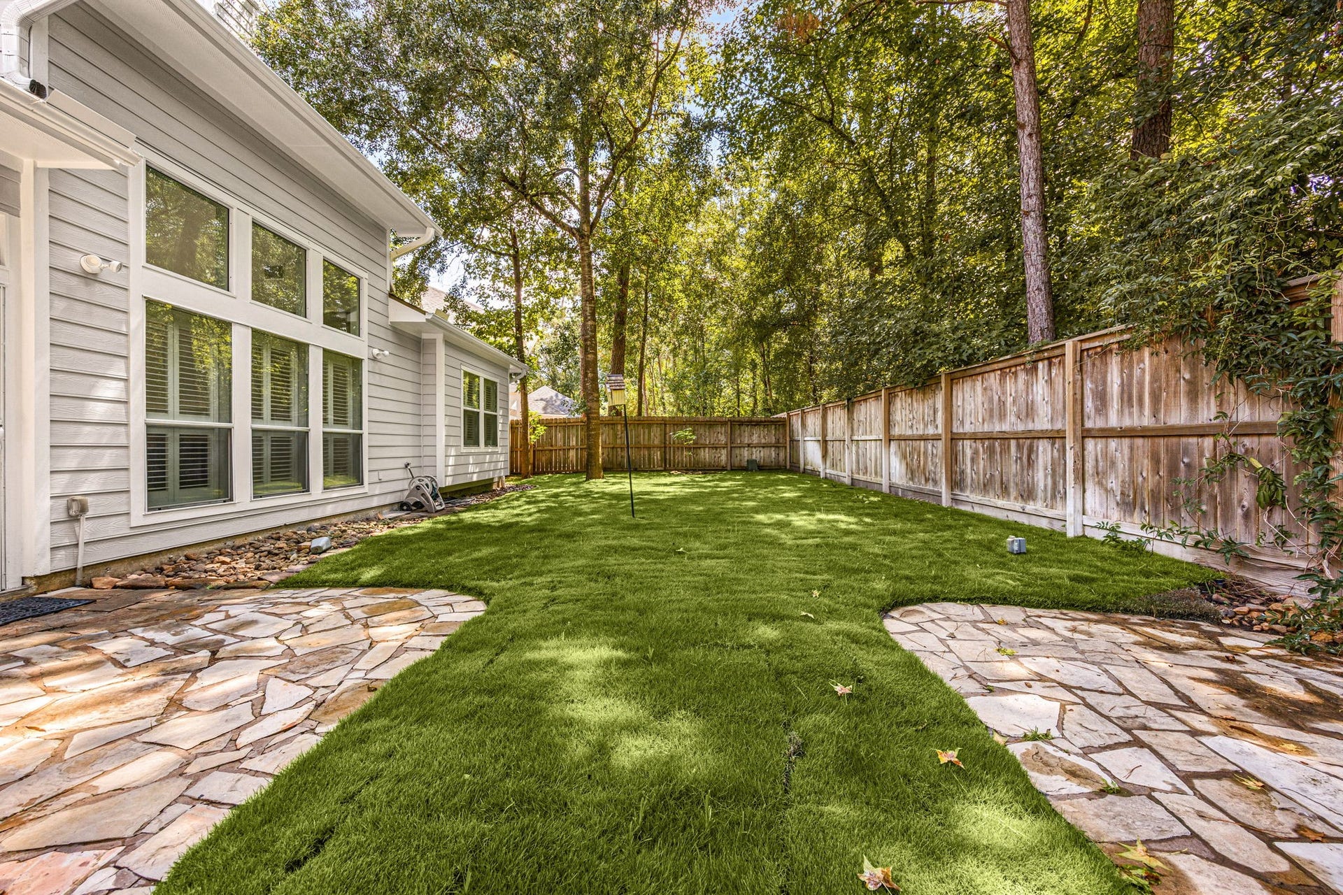 23 Pipers Meadow Street, The Woodlands, TX 77382 This perspective showcases the towering mature trees that border the property, bringing a peaceful nature-filled atmosphere directly to your backdoor.