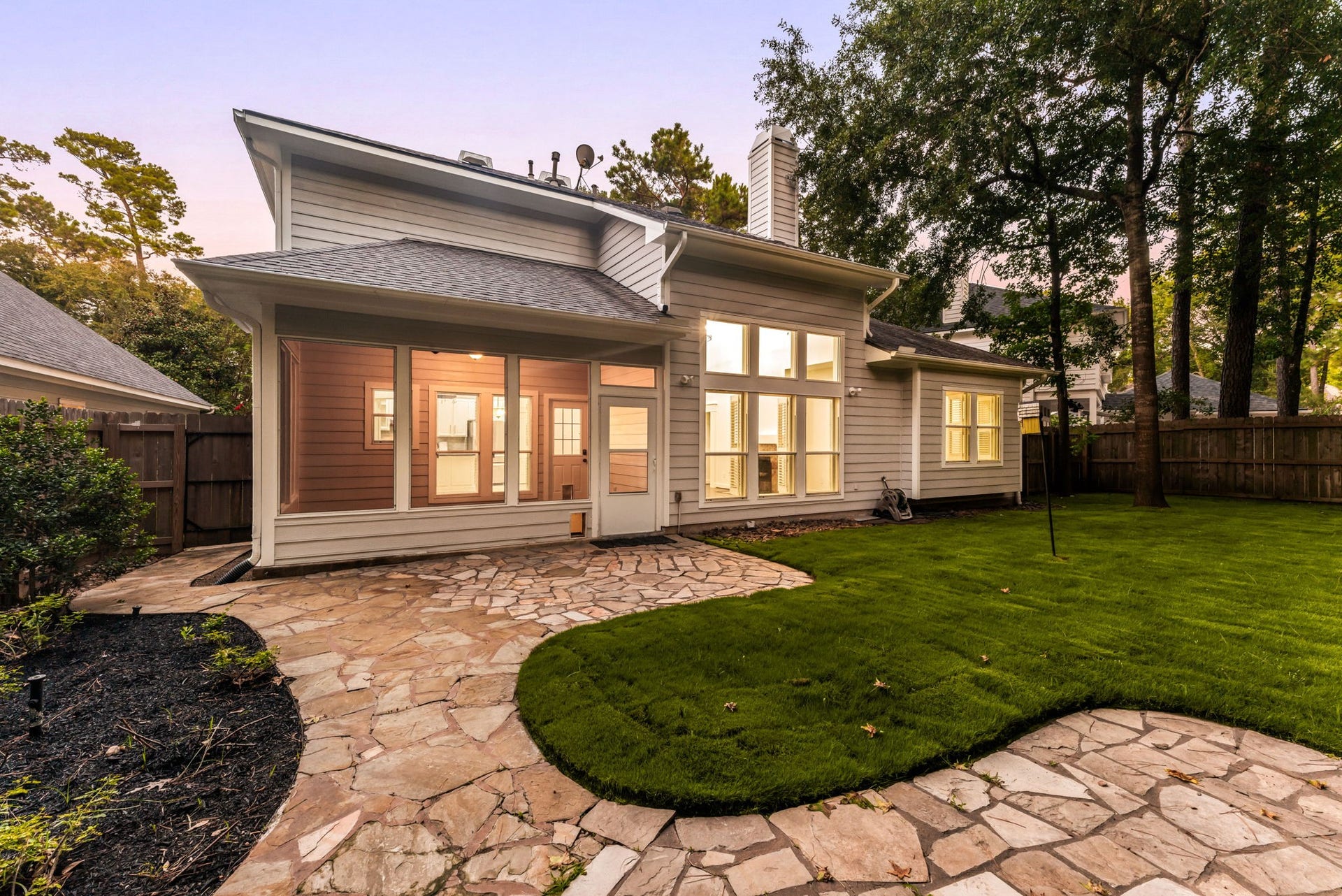 23 Pipers Meadow Street, The Woodlands, TX 77382 Your private outdoor oasis. The fully fenced backyard features a beautifully integrated flagstone patio, lush green lawn, and mature trees, creating a peaceful and serene setting.