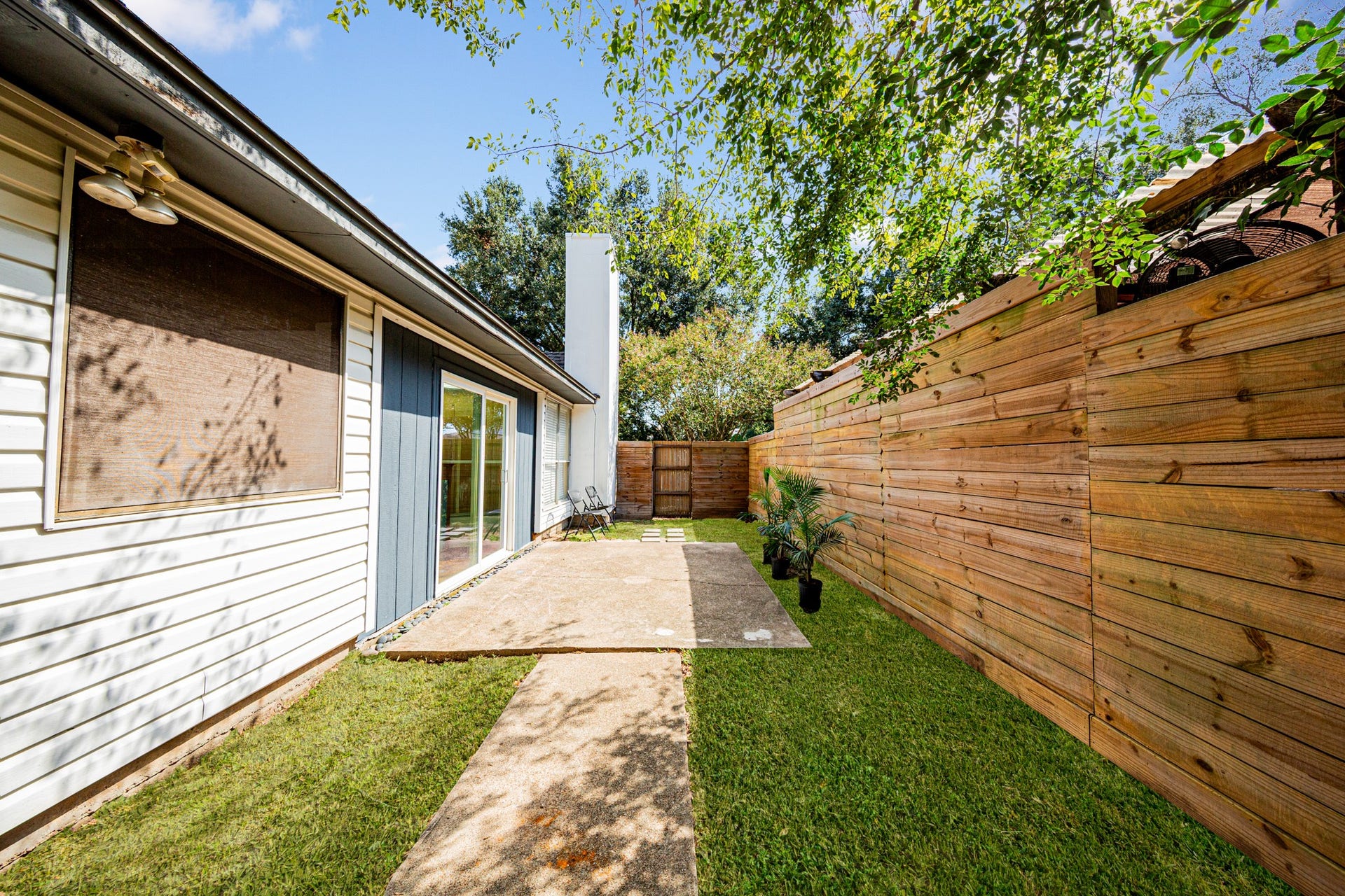 2107 Foundary Drive, Katy, TX 77493 Step outside to a private backyard retreat featuring a concrete patio, mature trees, and a beautiful horizontal wood privacy fence.