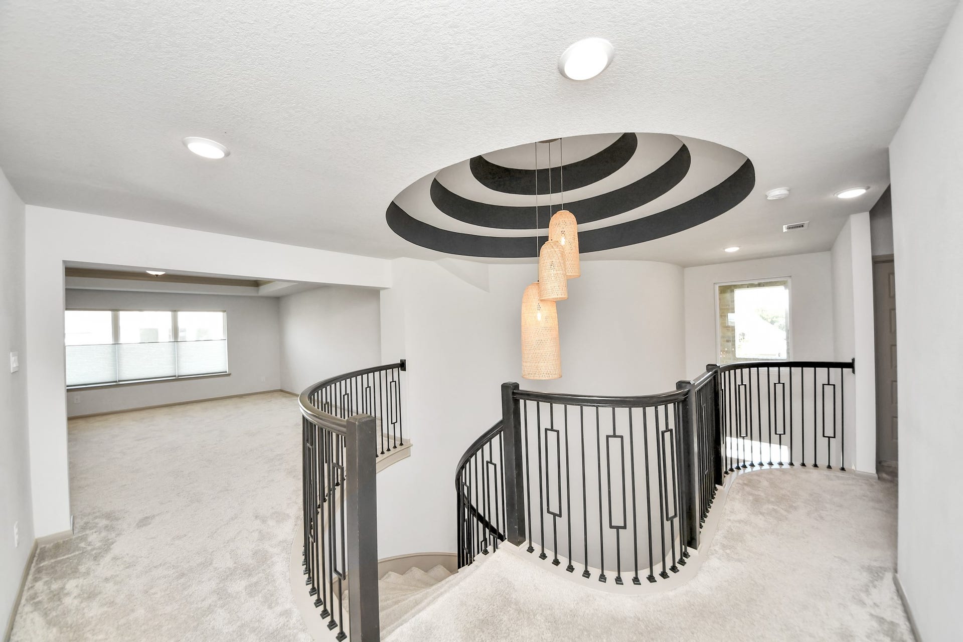 1423 Hackberry Heights Drive, Richmond, TX 77406 Elegant spiral staircase with chic black railings, complemented by modern pendant lighting and plush carpeting, leads to a spacious, light-filled upper level.