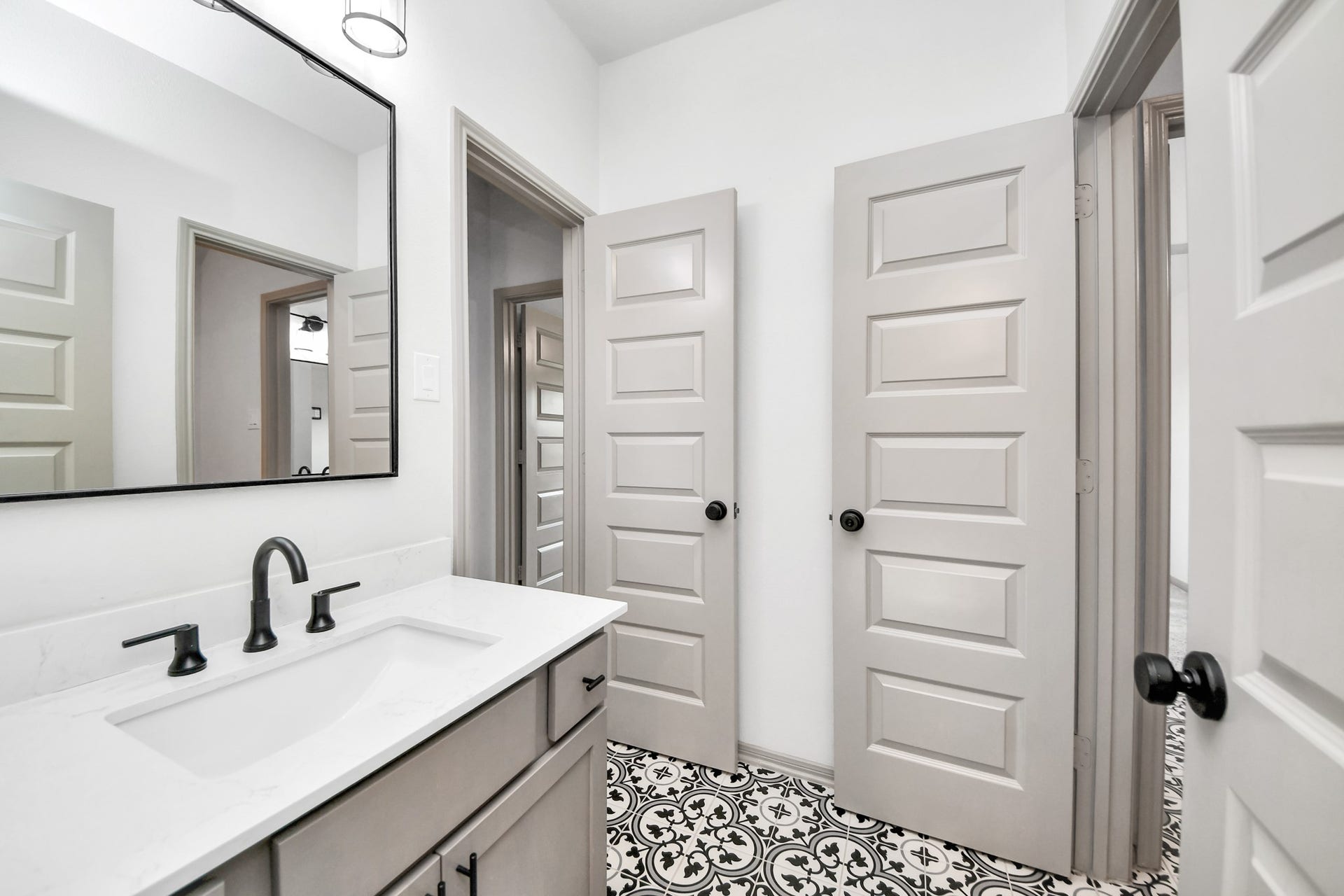 1423 Hackberry Heights Drive, Richmond, TX 77406 Charming bathroom featuring a sleek vanity with a modern black faucet, elegant patterned floor tiles, and stylish paneled doors adding character to the space.