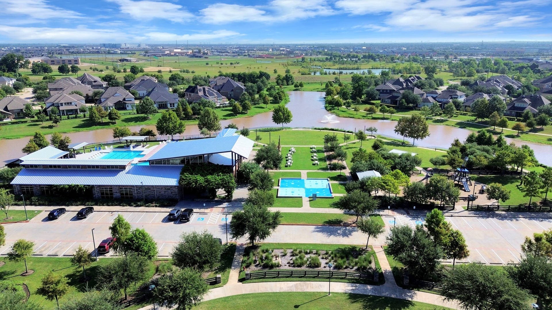 1423 Hackberry Heights Drive, Richmond, TX 77406 Stunning community view showcasing a spacious clubhouse with a pool, surrounded by lush greenery, serene water features, and beautifully landscaped walking paths.