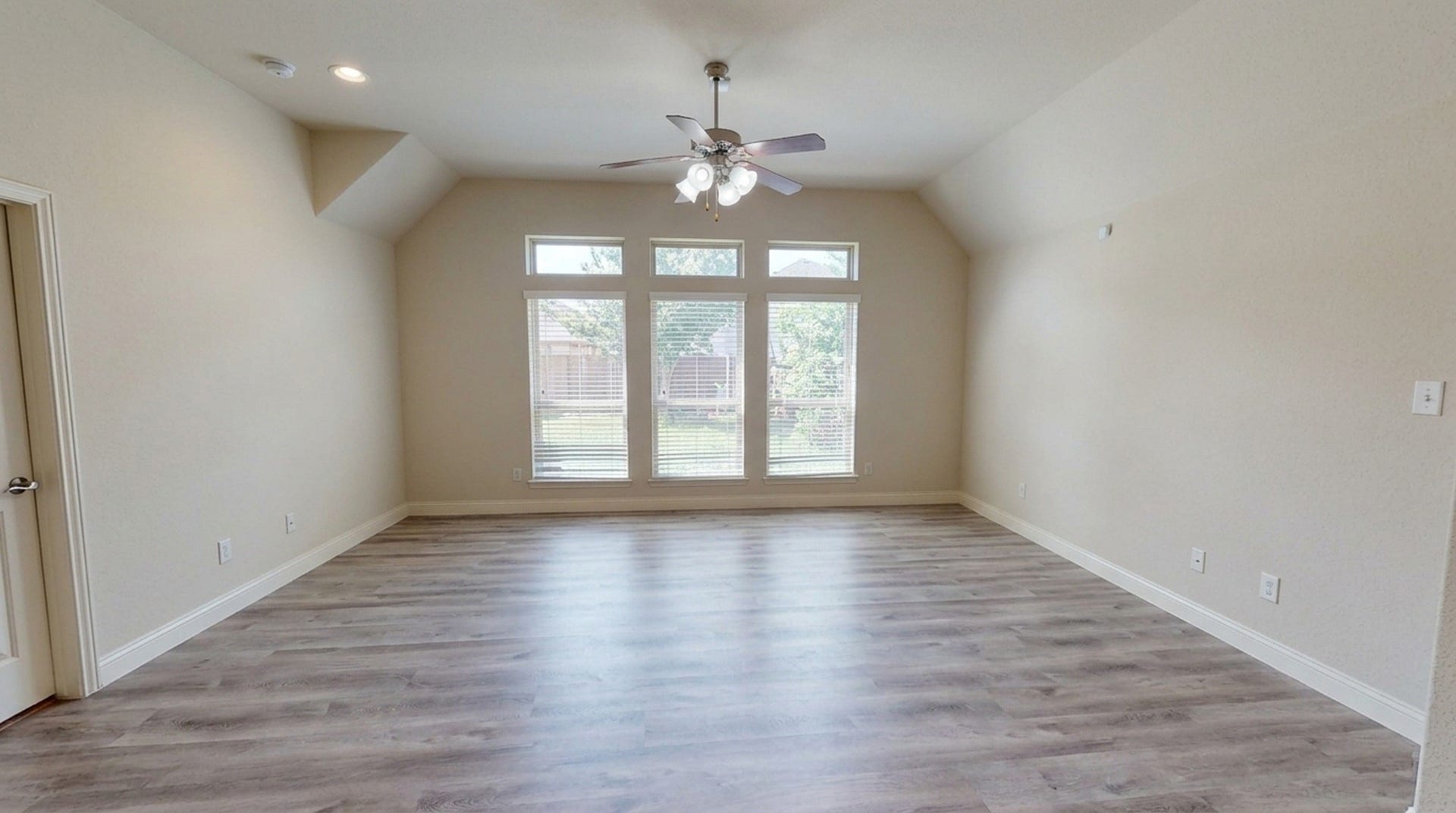 Spacious master bedroom area with high ceilings, abundant natural light from large windows, and elegant wood flooring, perfect for relaxation and entertaining.