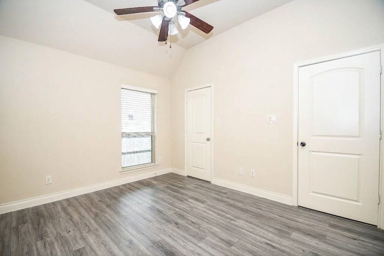Bright room with vaulted ceilings, elegant wood flooring, a ceiling fan, and ample natural light from the window.