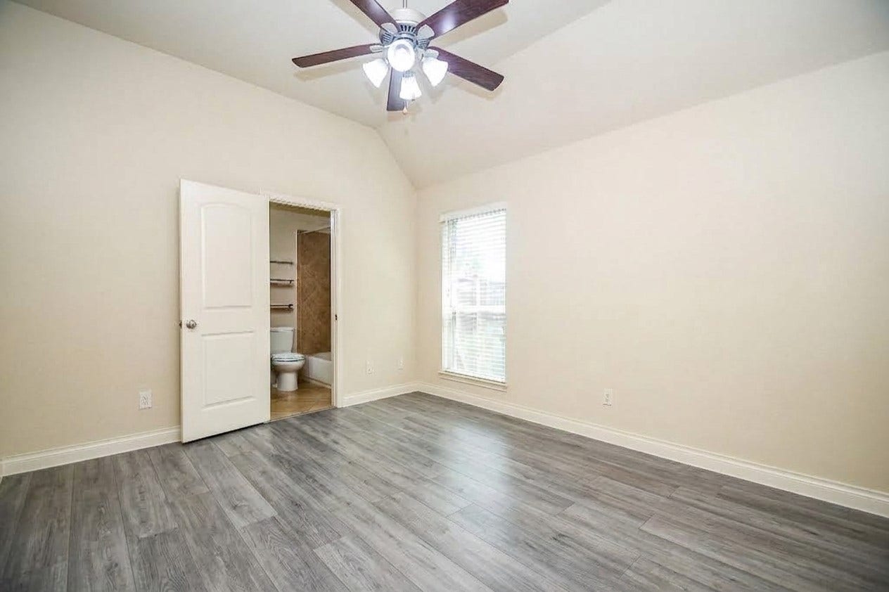 Bright bedroom with sleek wood flooring, a ceiling fan, and an en-suite bathroom.