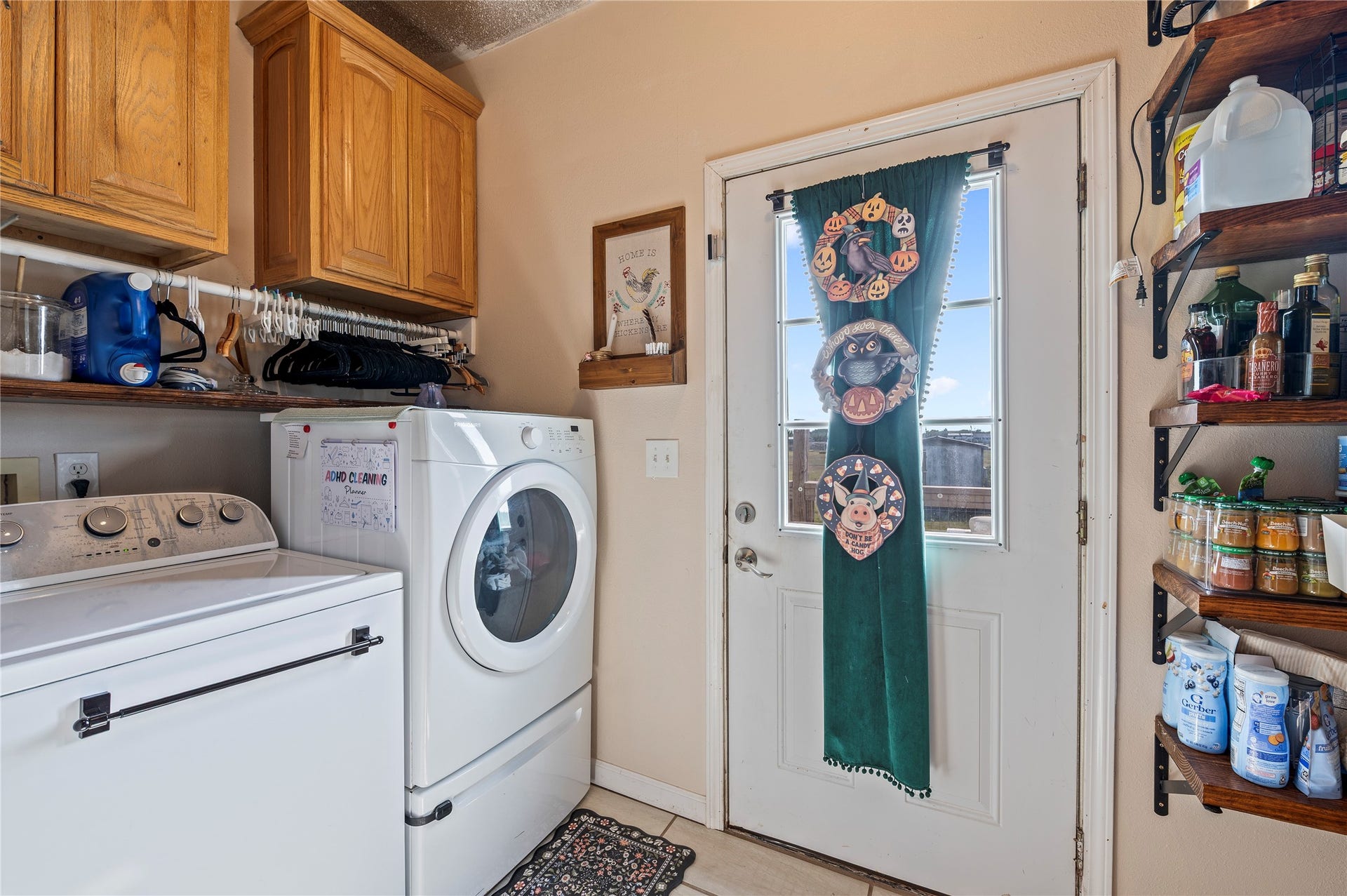 2337 Avenue D, San Leon, TX 77539 Tiled utility room area with washer/dryer, wood cabinets, and back deck/patio access.