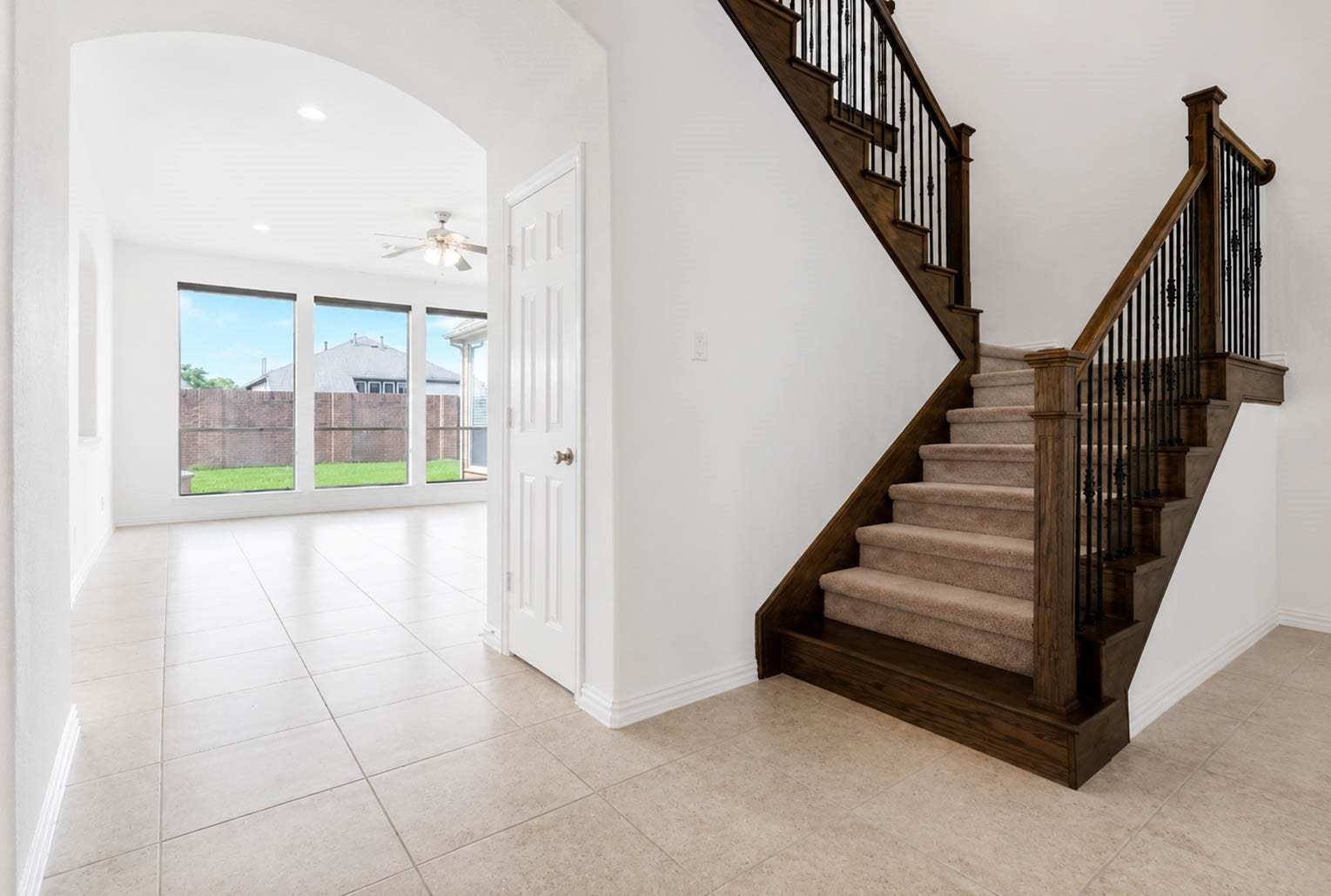 3814 Bluffstone Court, Sugar Land, TX 77479 Beautiful staircase with rich wood detailing and wrought iron balusters leads toward the light filled rear living space.