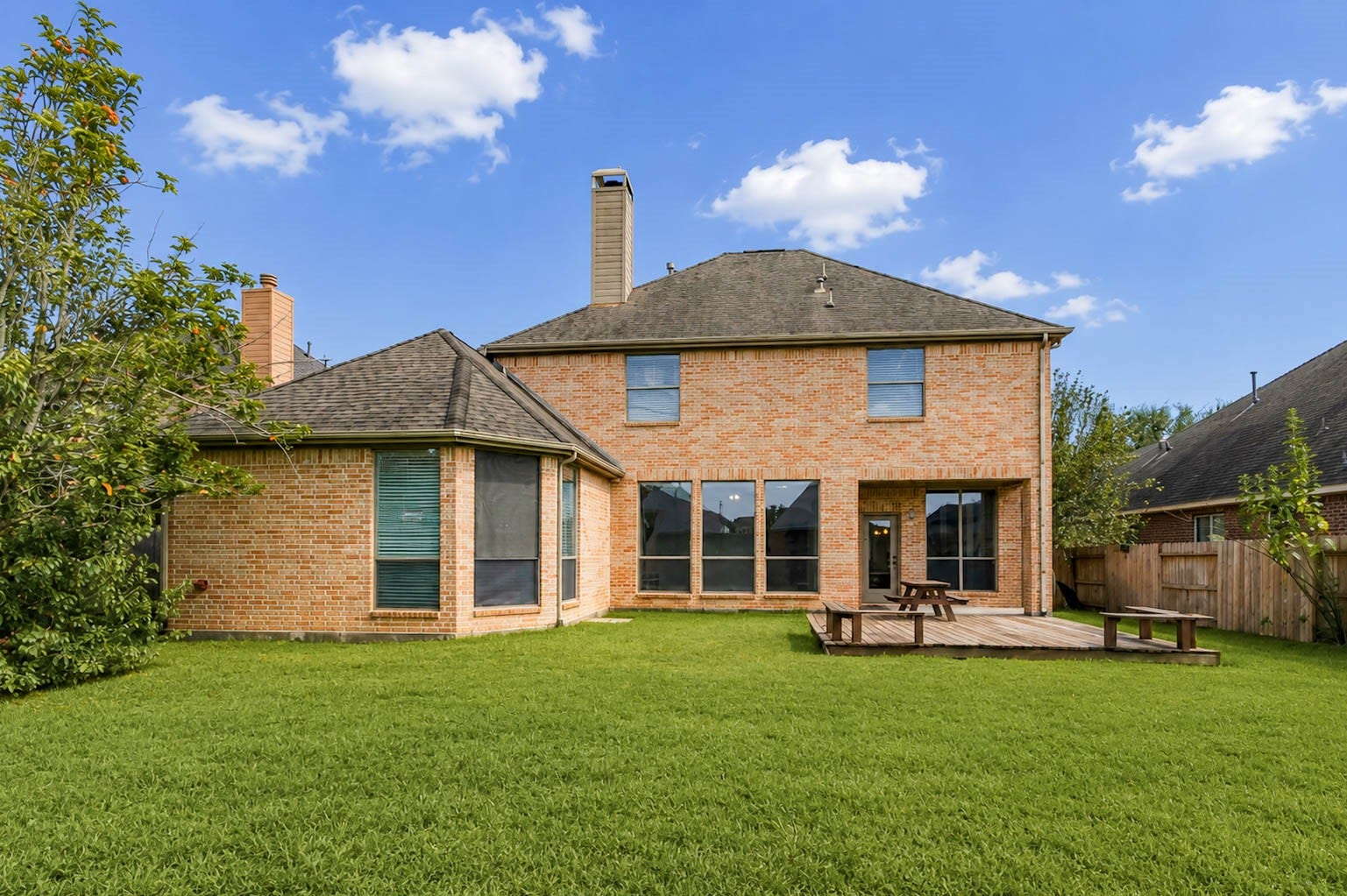 3814 Bluffstone Court, Sugar Land, TX 77479 Wide backyard view showcasing the home's generous green space, mature landscaping and brick exterior.