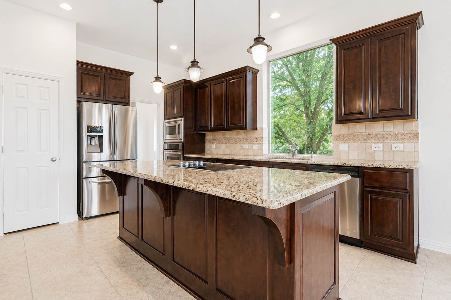 3814 Bluffstone Court, Sugar Land, TX 77479 Spacious kitchen anchored by a generous granite island, rich cabinetry, stainless steel appliances and an oversized window bringing in natural light.